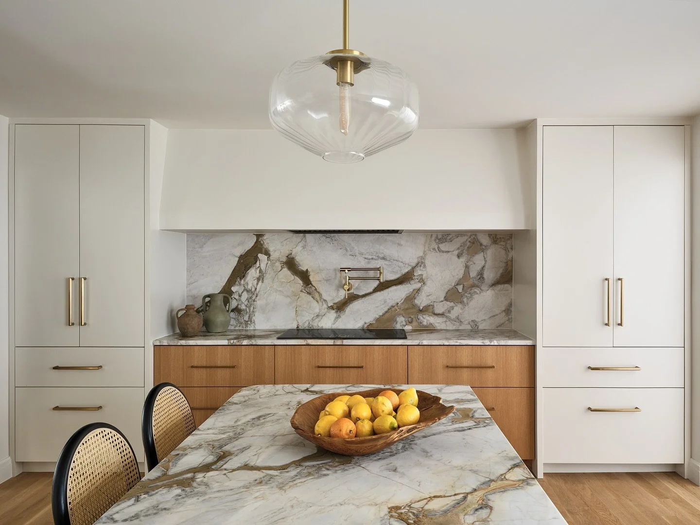 Our Westport modern kitchen features a colorful quartzite countertop and backsplash that is balanced by symmetrical cabinetry around the range hood enclosure.