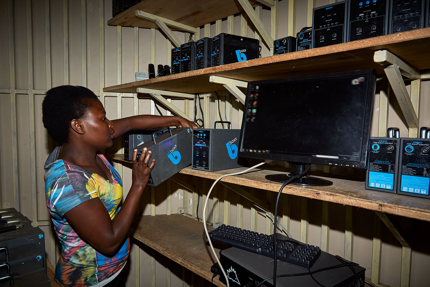 Jennifer, student at Green Malata, works at the electric kiosk, where solar batteries are rented out to the communities, Luchenza, Malawi, 2017.  Green Malata, an entrepreneurial training village that offers a variety of green alternatives to Malawi