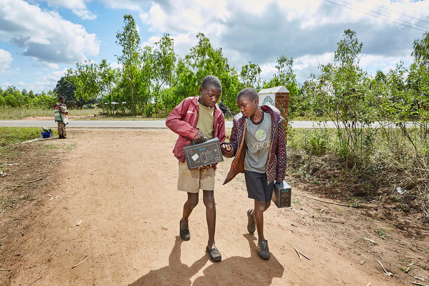  From left to right: Jan Chumba (12) and his brother Ben (10) carry two solar batteries home, after picking them up at Green Malata, an entrepreneurial training village that offers a variety of green alternatives to Malawi’s notoriously unreliable na