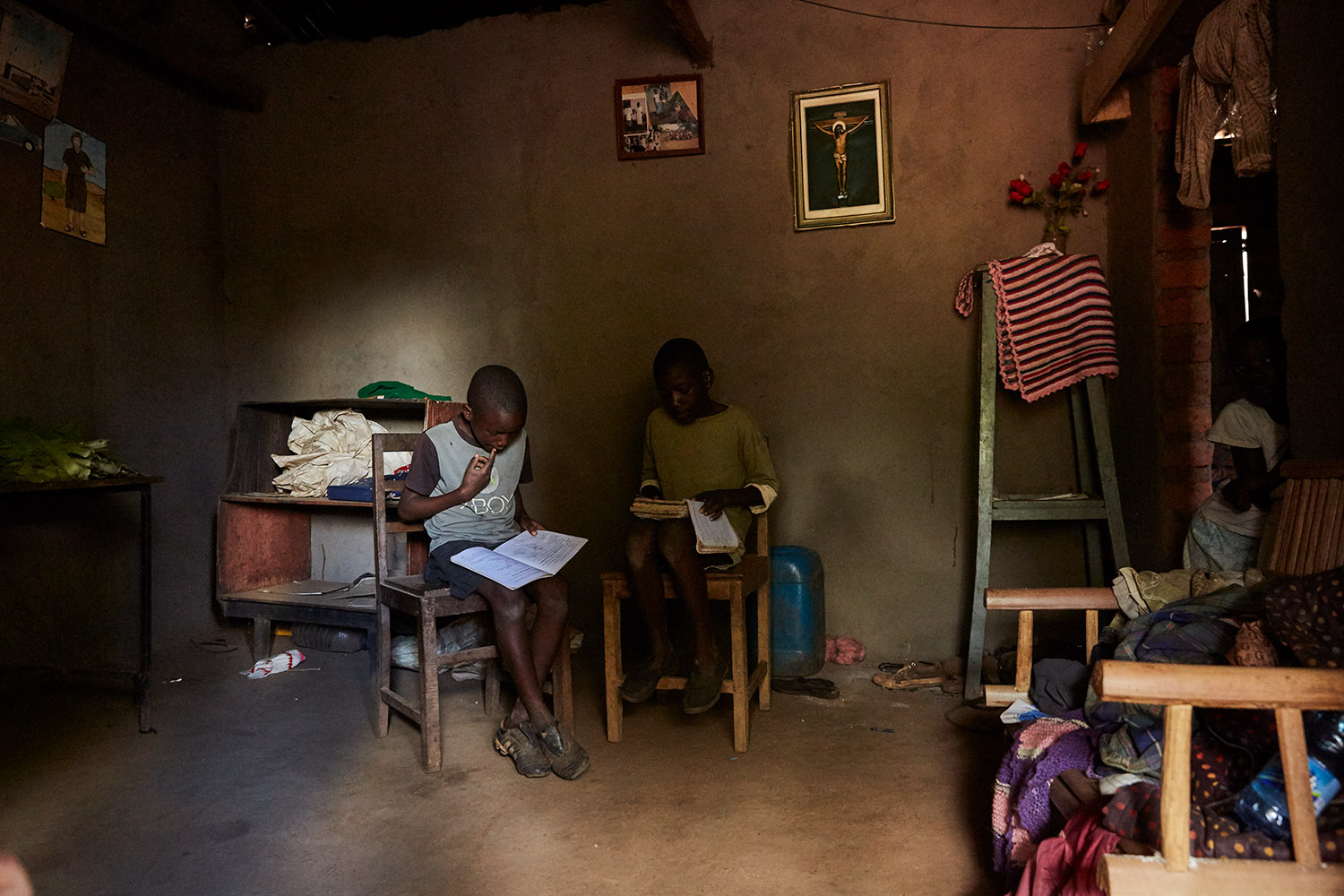  Jan Chumba (12) and his brother Ben (10) studying at home with the daylight that falls into their home, Luchenza,  Malawi, 2017. 