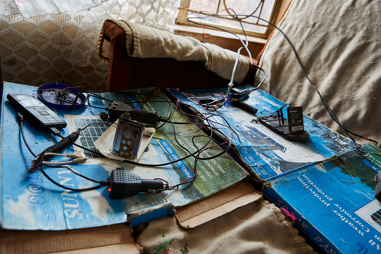  The charging station in the living room of Felix Wonga’s home, Luchenza, Malawi, 2017.  The solar panels that Felix uses for his mobile phone charging business also powers their lights, and several small radio’s and speakers. Felix: “We are the only