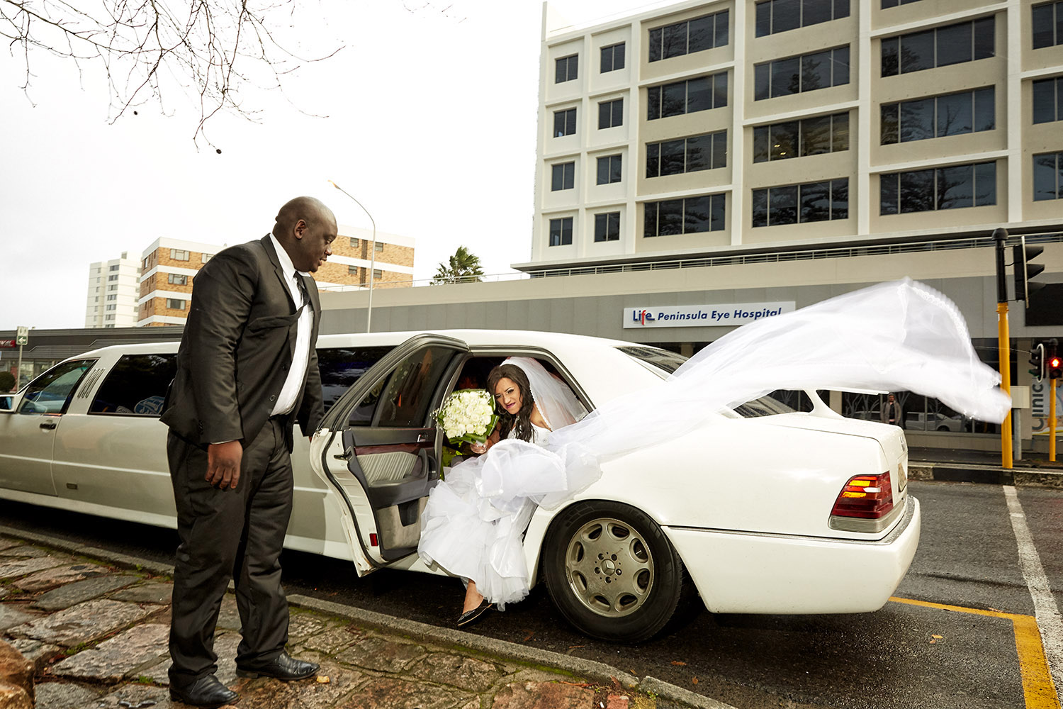  Chedino gets out of the limousine at Claremont Gardens, a famous spot for wedding pictures, Claremont Gardens, Cape Town, 2018. The weather was so bad that, moments later, Chedino decided not to go ahead with her pictures, and told the driver to tak