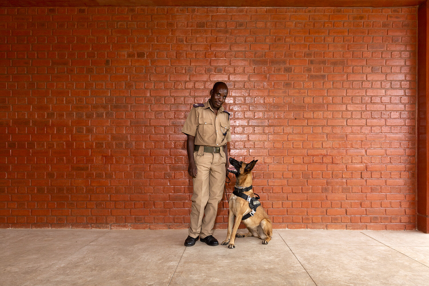  Wildlife Detection Dog Unit (WDDU) handler Kinord and dog Danna take a break from searching the luggage of departing passengers at Kamuzu International Airport (KIA), Lilongwe, Malawi, 2020. 