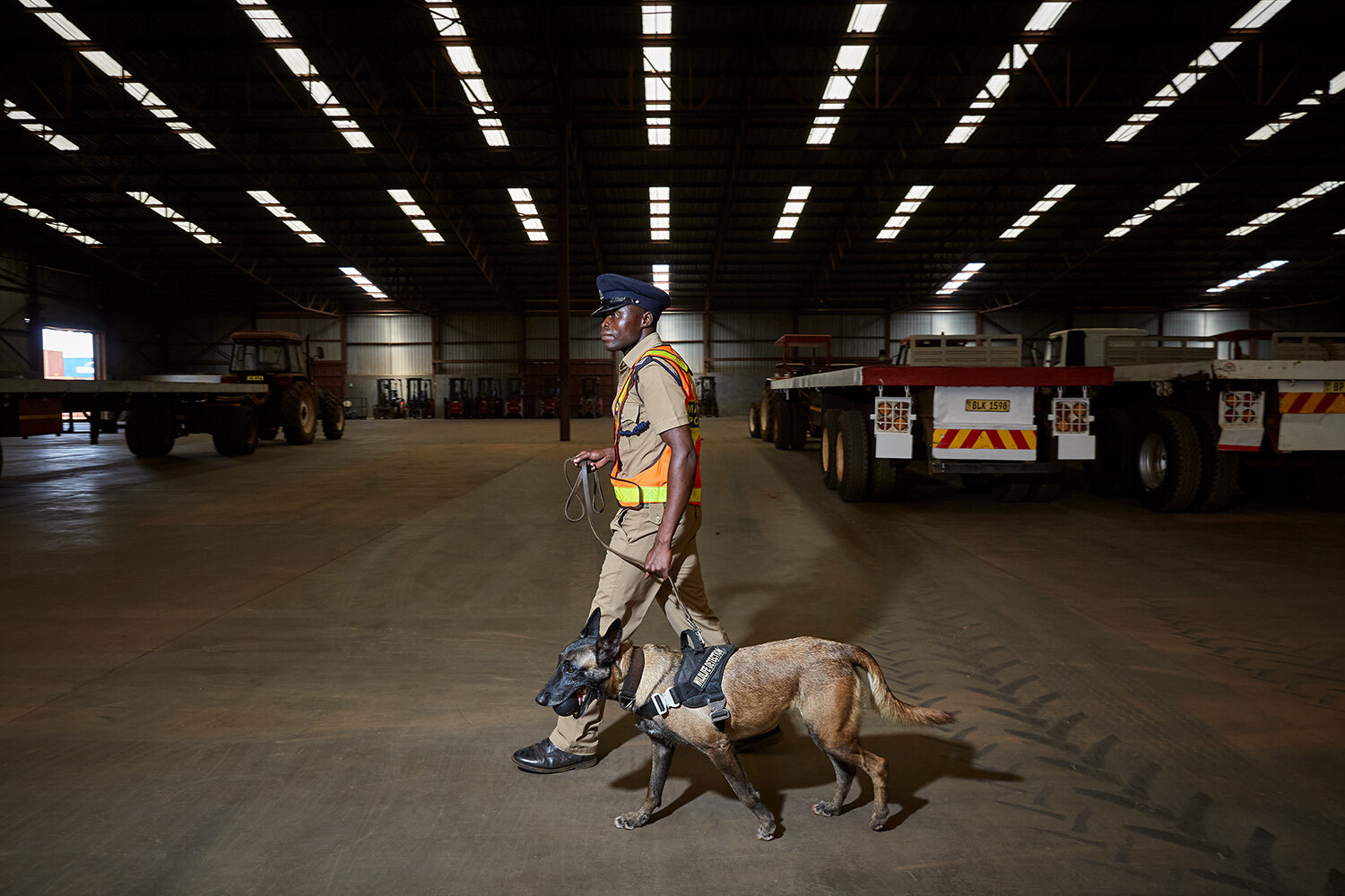  Wildlife Detection Dog Unit handler Benjamin and dog Nikita walk through a loading hall at Bridge Shipping during a training session, Lilongwe, Malawi, 2020. 