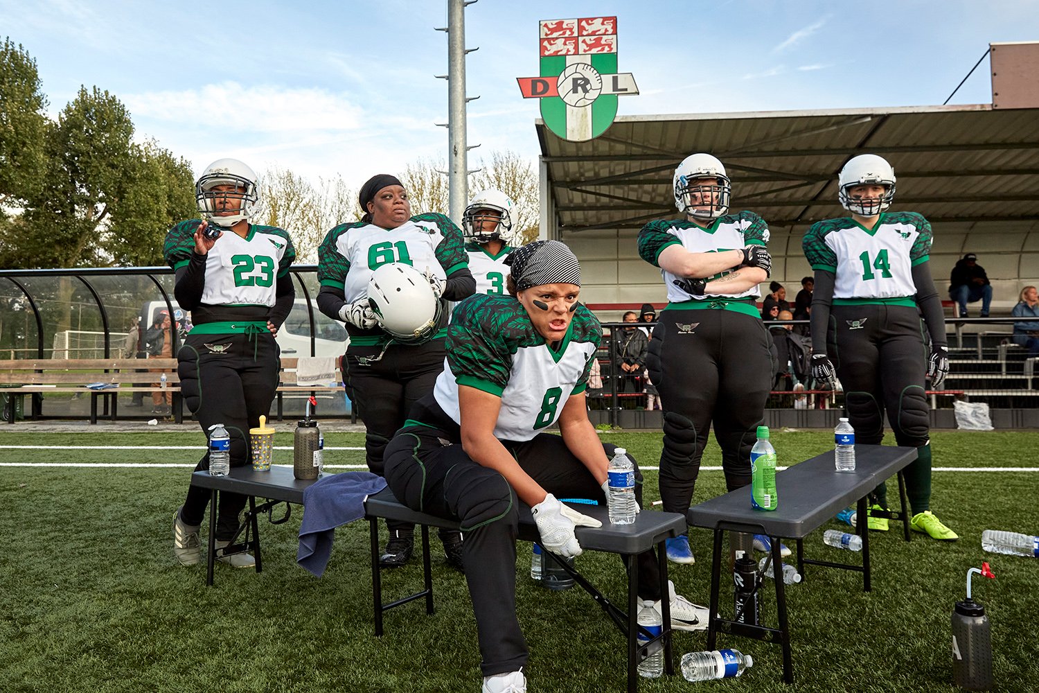  Together with her teammates, Dalila, a defensive end for the Rotterdam Ravens (center foreground), looks on as the Ravens' offense plays against the Eindhoven Valkyries, Rotterdam, NL, 2021. 