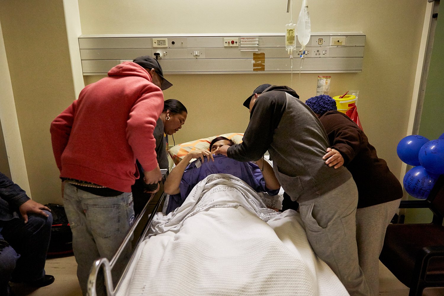  In the evening after her gender-affirming surgery, Chedino shows off her new breasts to Keagan and his mother (right) and a few of her friends, Groote Schuur Hospital, Cape Town, 2017. 