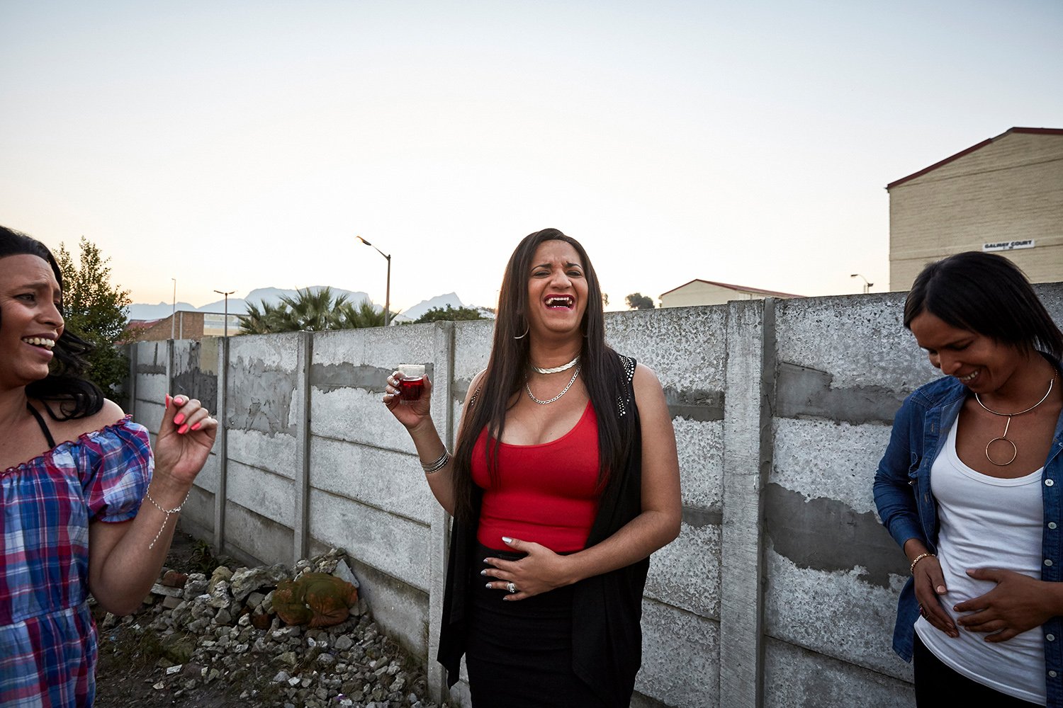  From left to right: Mortavia, Chedino and Wilma share a joke in the courtyard of the home she shares with Keagan and his parents, Hannover Park, Cape Town, 2018.  