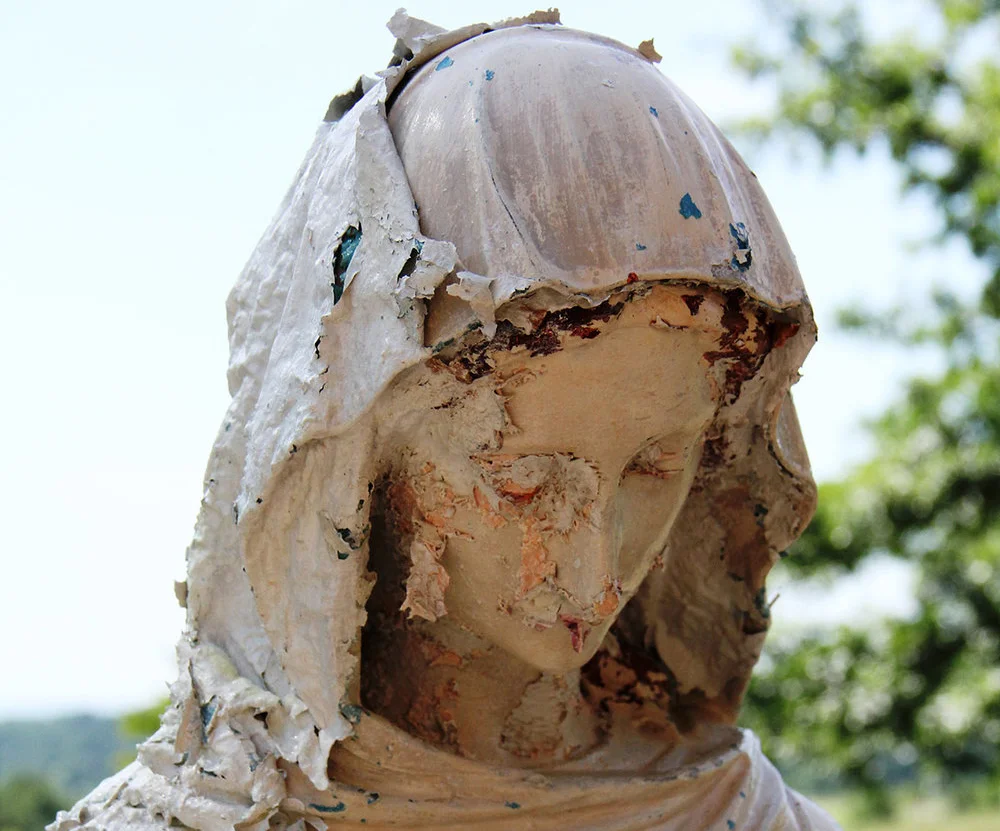 A marble sculpture covered with layers of flaking paint.