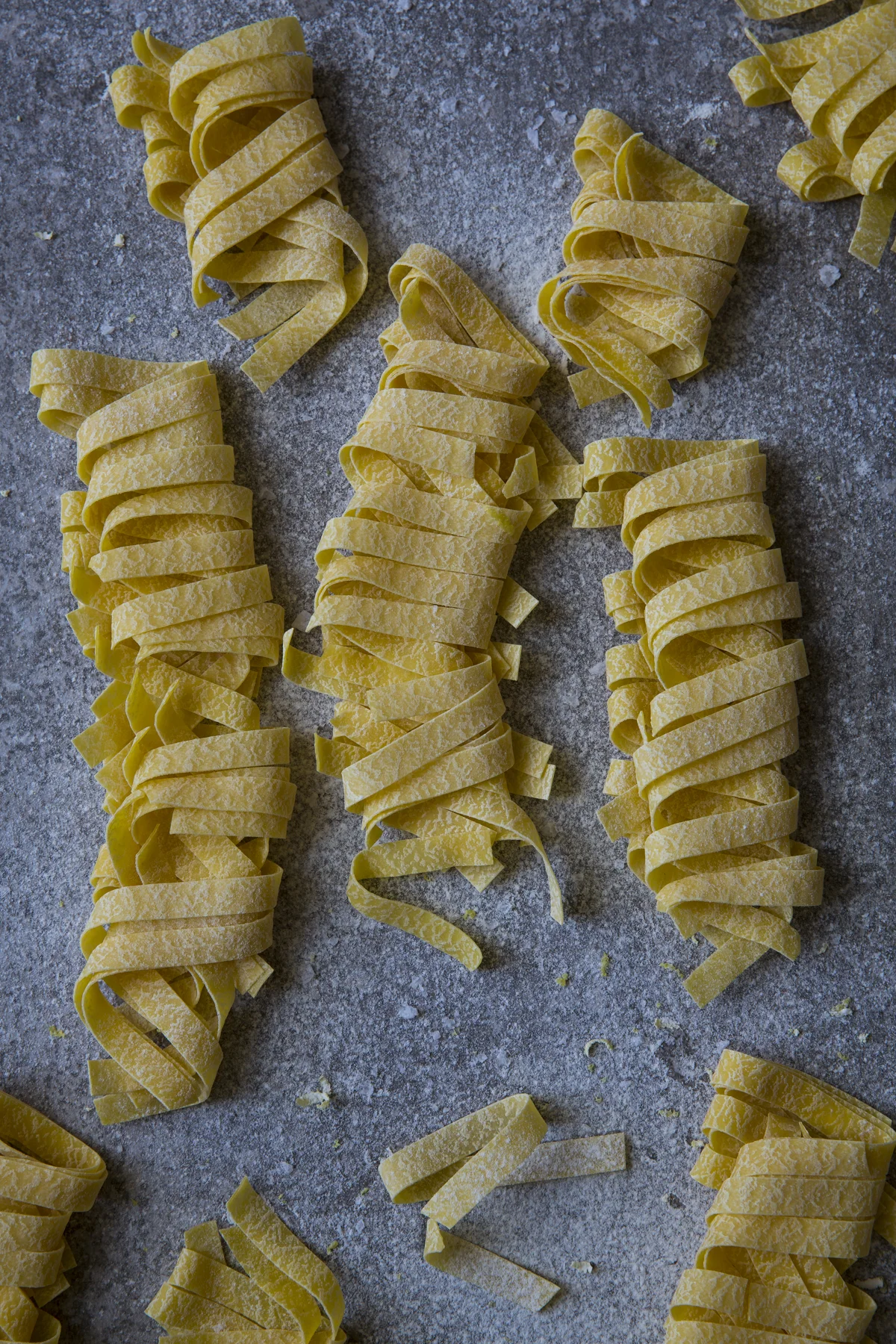6. Final sprinkle of flour, salt, pepper and zest. I’m happy with this as my final image. Tips: I started with a textured background. And then I layered the image with more texture, the flour, salt and pepper both before I added the pasta and after. Textures and layering add depth and make an image look more natural and real. Always, always pick the best looking food. Be really mindful that you have selected the prettiest cherry or the most perfect basil leaf. This doesn’t mean that it has to be EU regulations correct, wonky carrots, and nobbly potatoes still with mud are beautiful in my opinion but no one wants to see bad bits or dead leaves. Just sometimes we are so busy trying to get everything else correct we forget about the subject so just keep this in mind! Have another go! As I had the set up all ready, I decided to do another shot with a different pasta shape and instead of filling the frame used the J shape to make this image. Story : The beauty of Conchiglie Light : Natural side light Camera Set Up : Overhead, Portrait. Canon 5D Mark III, 24-70 Lens, a tripod, settings Aperture F/8 Shutter Speed 1/25 ISO 200 Styling Choice: J shape Colour Wheel: Complimentary colours, with the blue shifted to a grey blue Props : Textured tile, plain flour, black pepper, sea salt, lemon zest