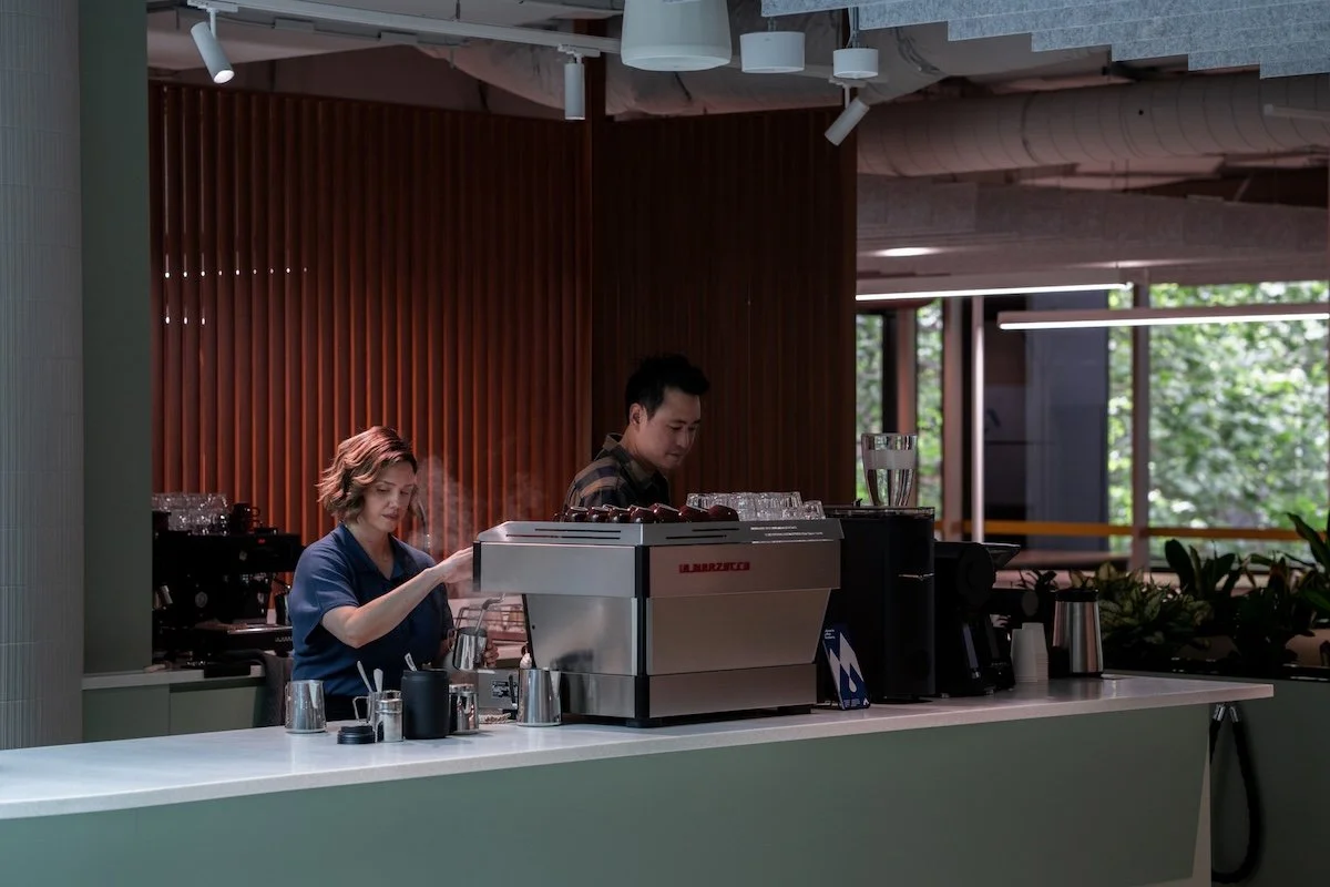Barista preparing takeaway coffees beside a professional espresso machine in a Melbourne café.