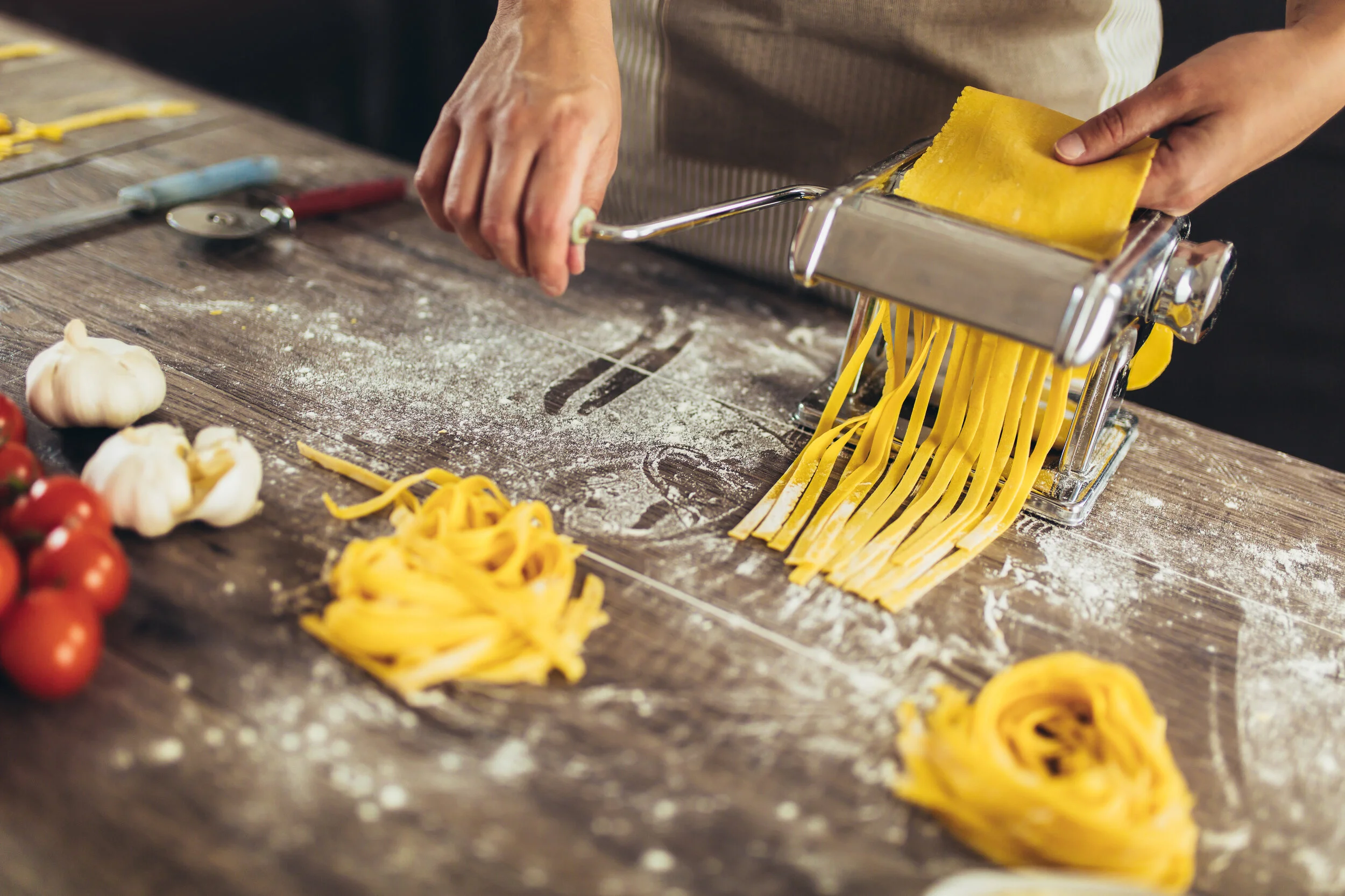 Preparing-home-made-pasta-with-pasta-maker-on-wooden-table.-1226174657_5760x3840.jpeg