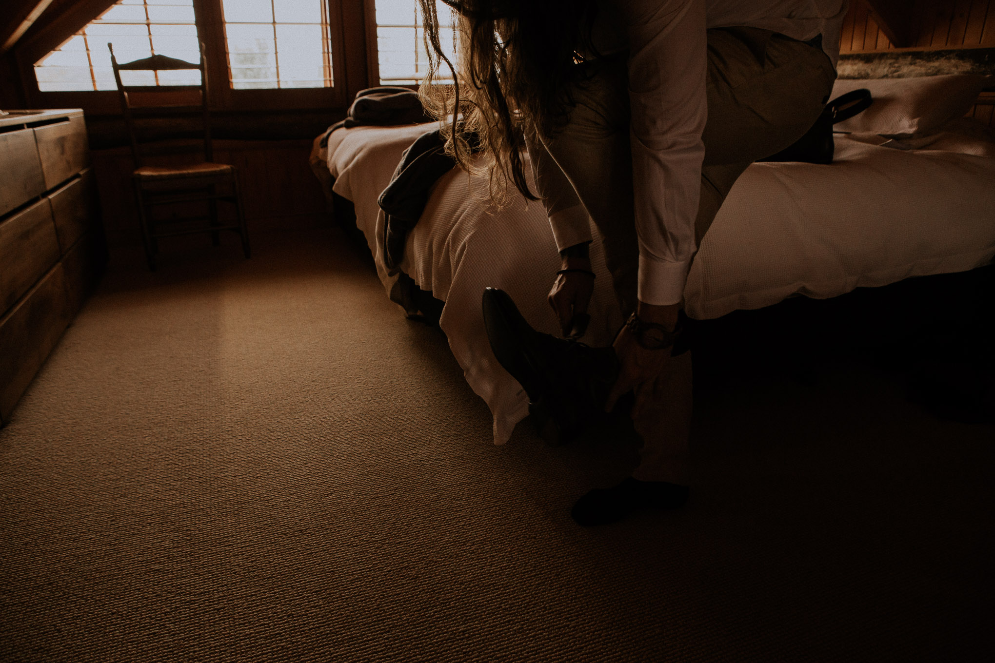 Groom getting ready in rustic timber cabin at Waldara Farm