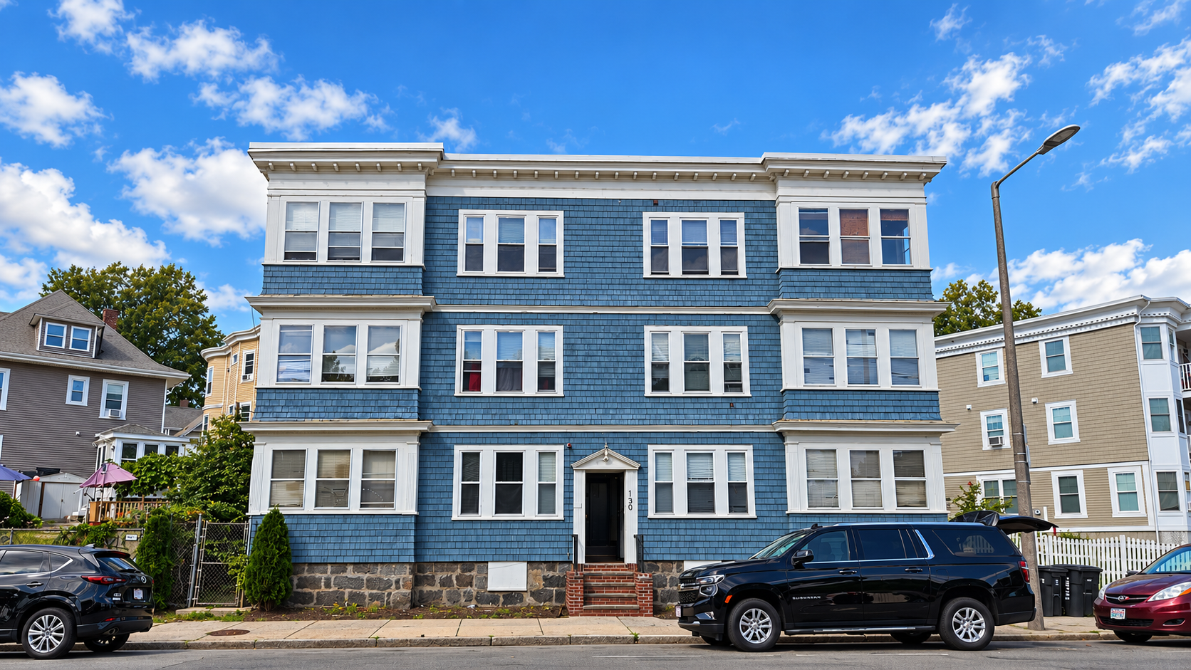 blue_shingle_apartment_building_on_a_sunny_street.png