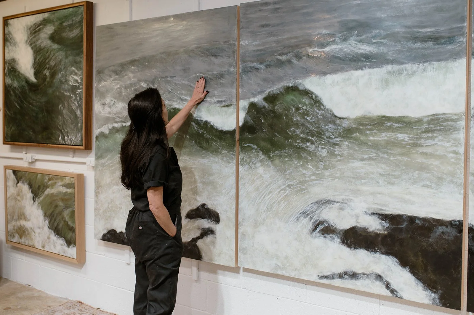 Artist in studio analyzing her waterscapes on her studio wall