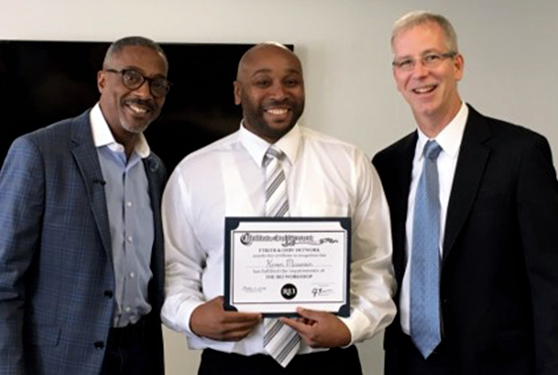 Tracey Syphax and C.J. Meenan present a reentry student with a program certificate.