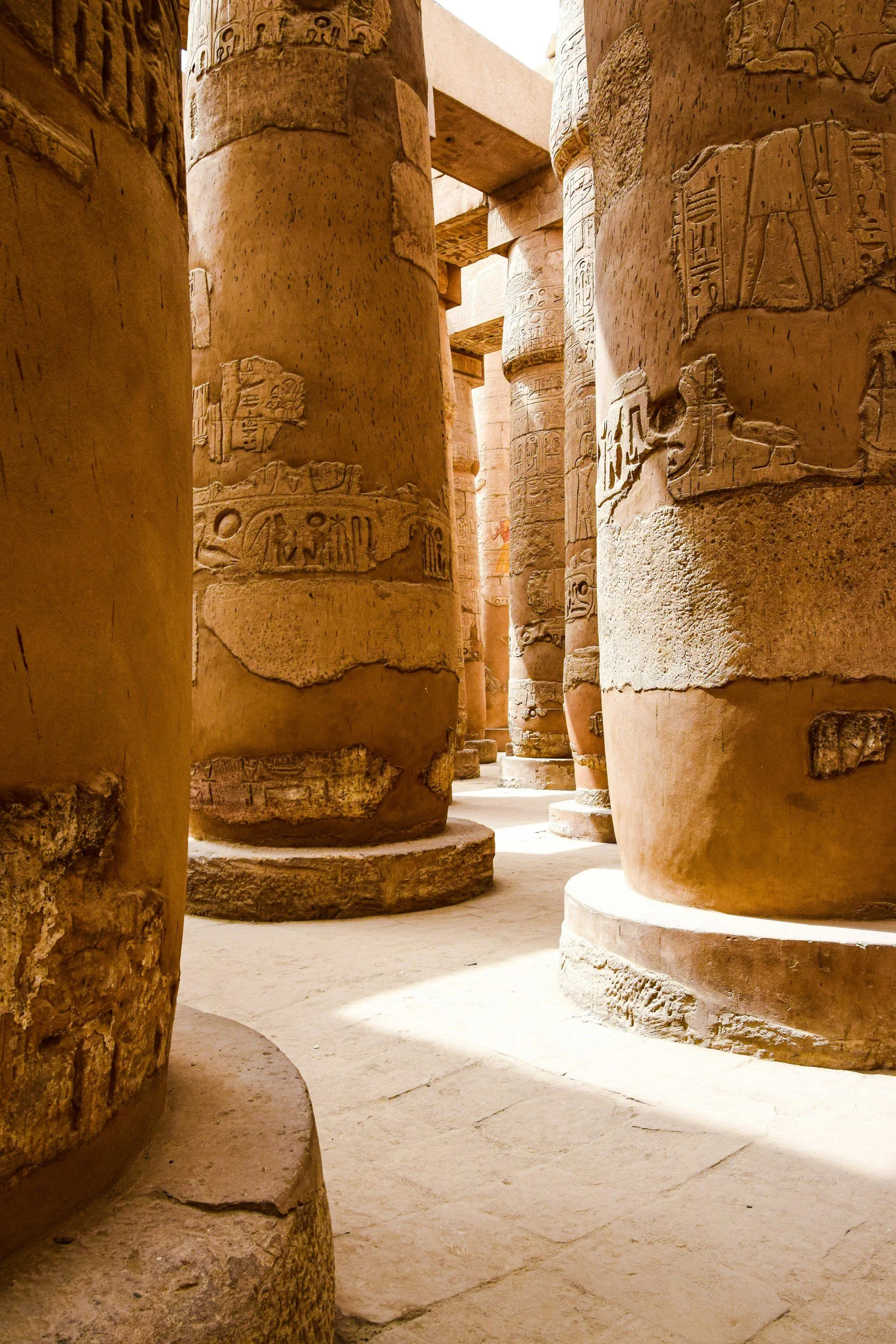 Close-up view of ancient Egyptian stone columns with hieroglyphic carvings, located in a temple or historical site.