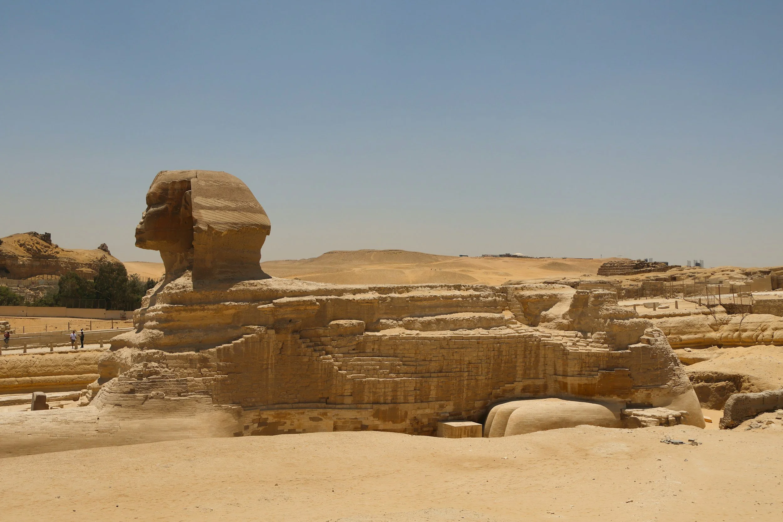 The Great Sphinx of Giza in Egypt, a limestone statue with the head of a human and the body of a lion, situated in a desert landscape under a clear blue sky.