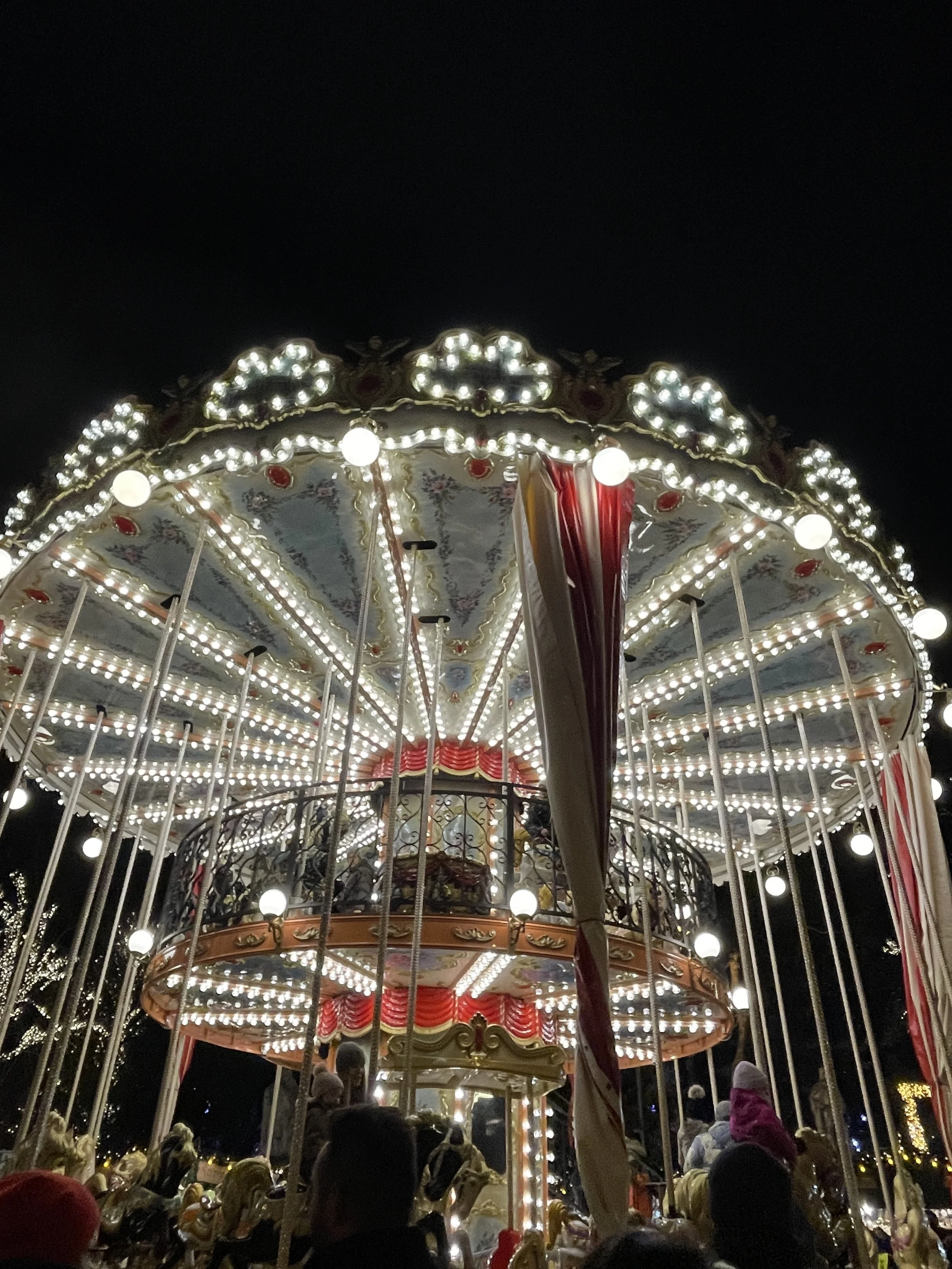 Brightly lit vintage carousel at night with ornate decorations and happy children riding.