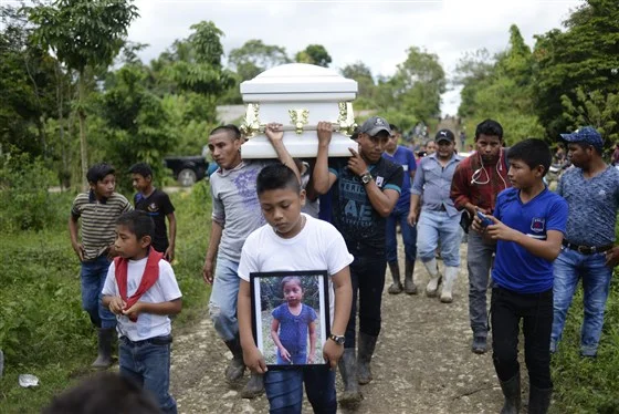 A boy carries a picture Jakelin Caal while her coffin is carried to the cemetery in San Antonio Secortez, Guatemala, on Dec. 25, 2018.Johan Ordonez / AFP - Getty Images