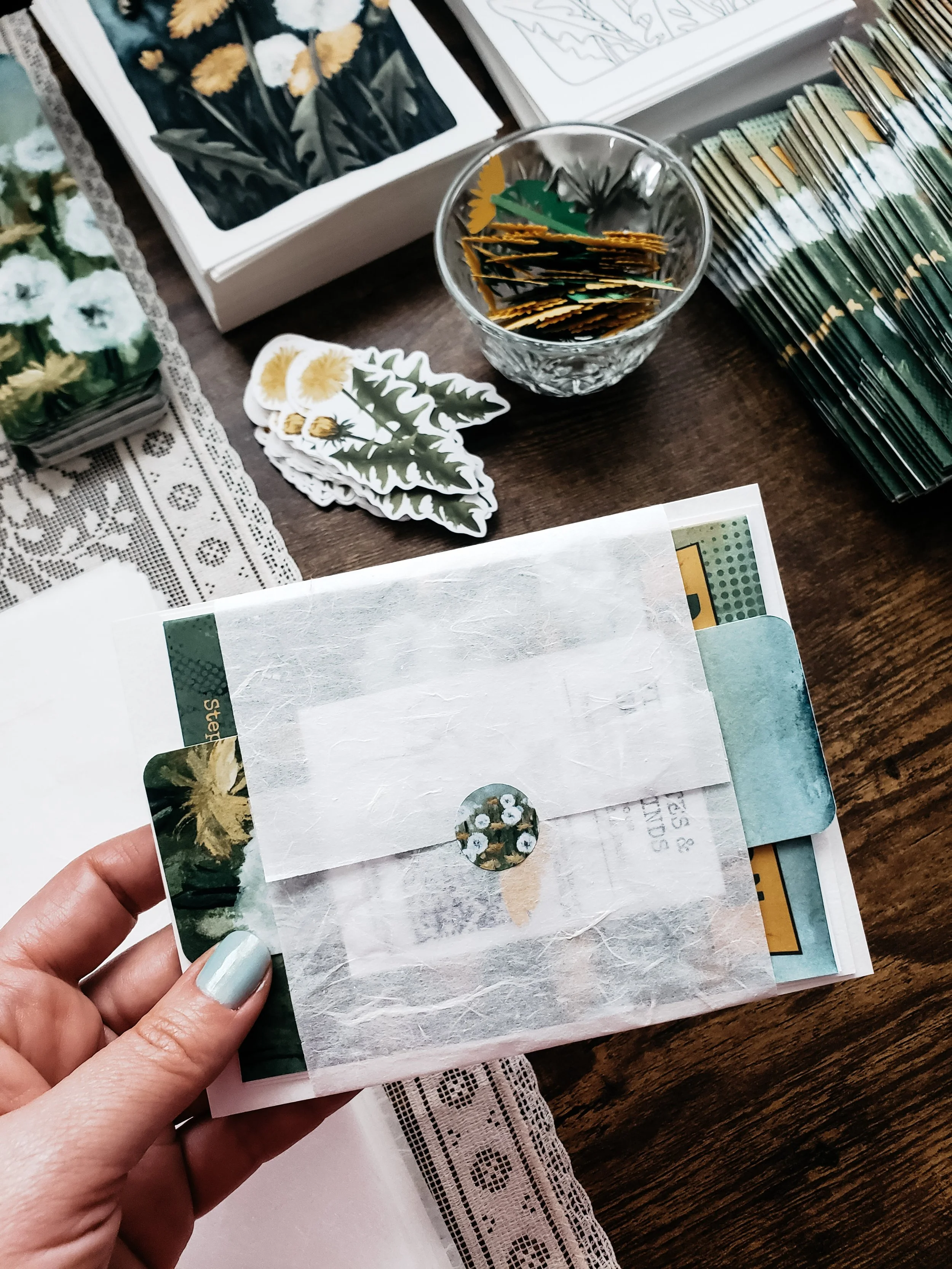 Hands placing dandelion mail club items into an envelope for shipping.