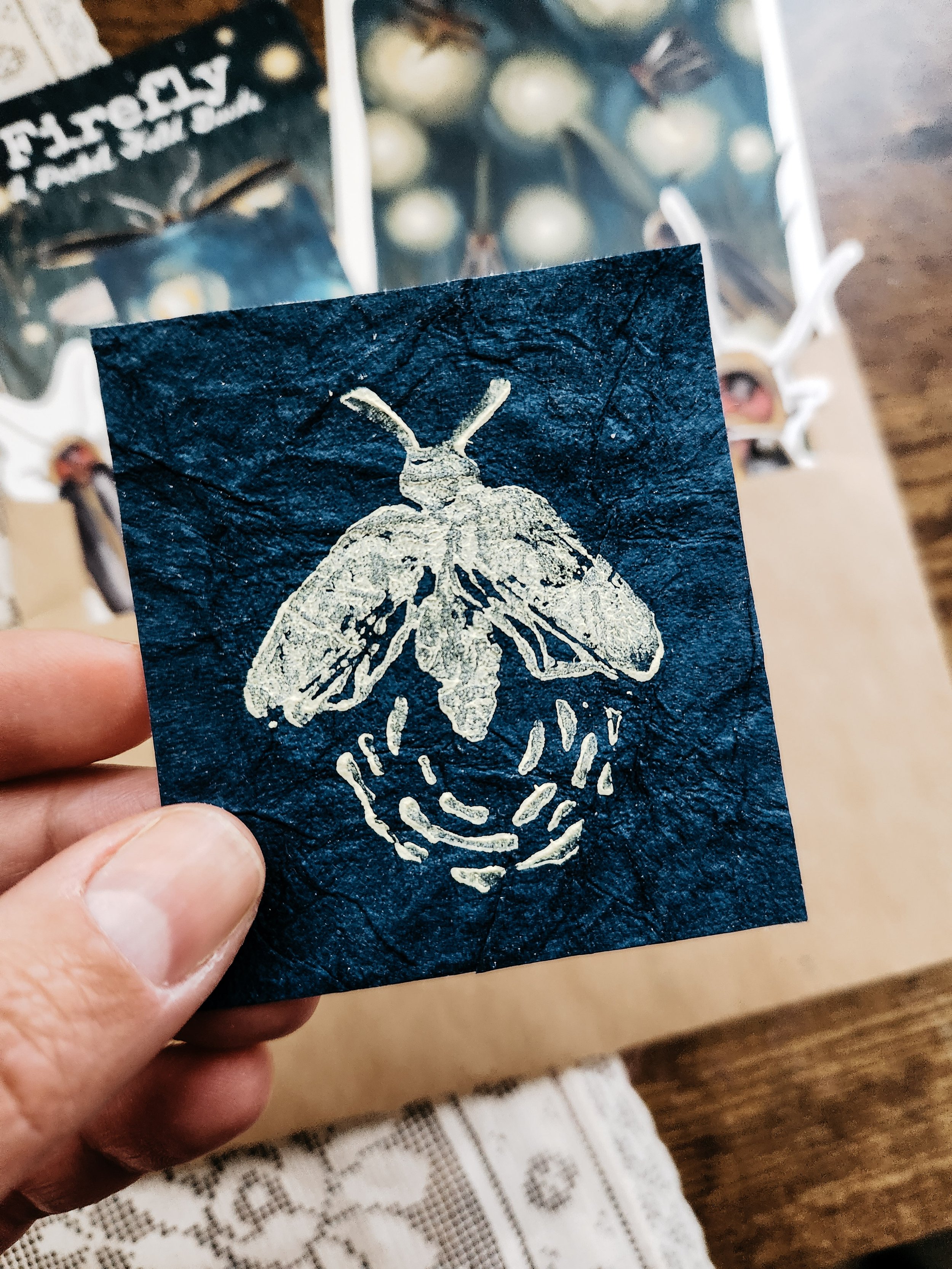 and-pulled firefly lino print on dark blue paper, individually printed by hand.