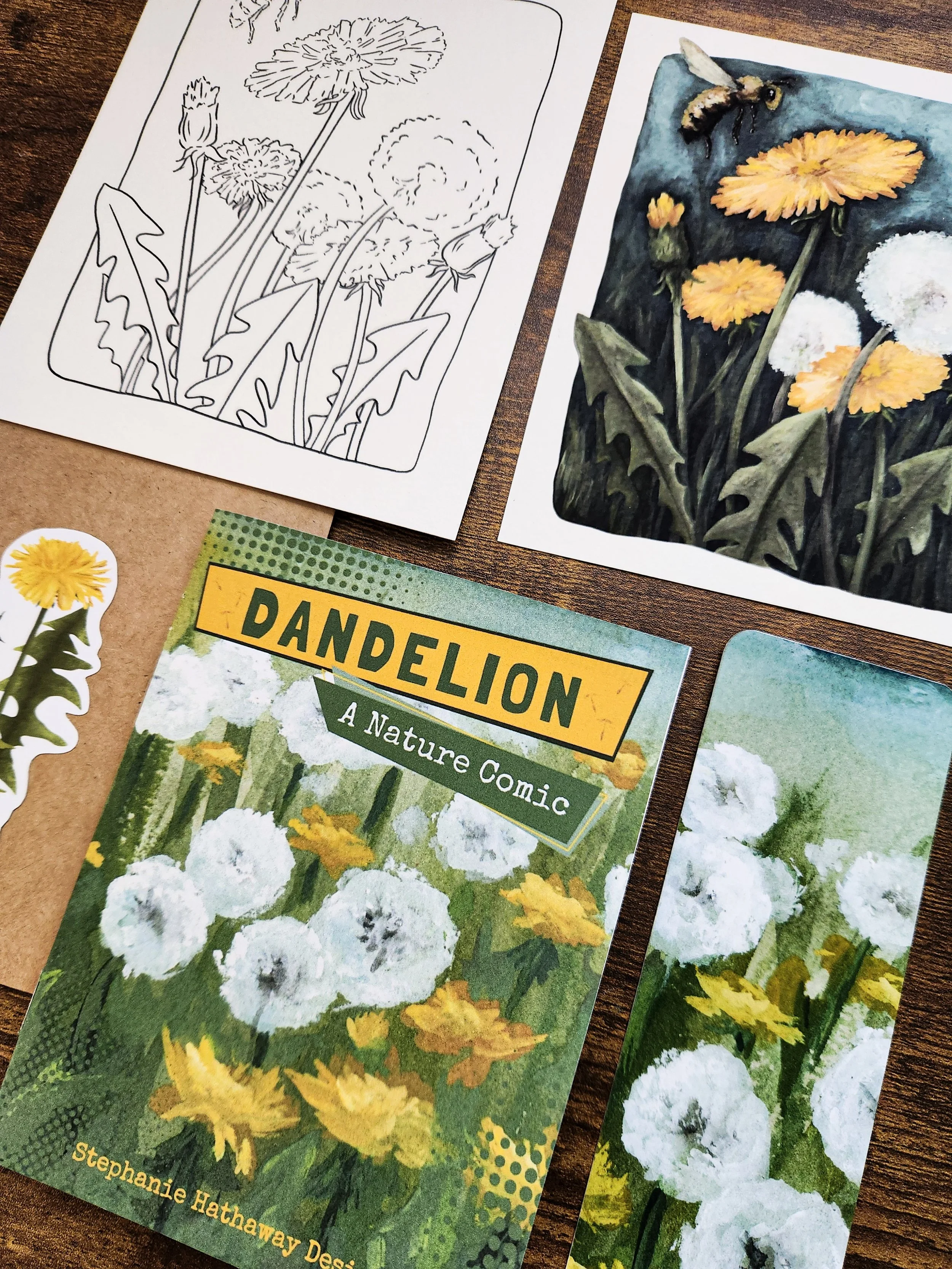 All dandelion mail club items arranged on a flat surface, including print, sticker, comic, bookmark, and paper elements.