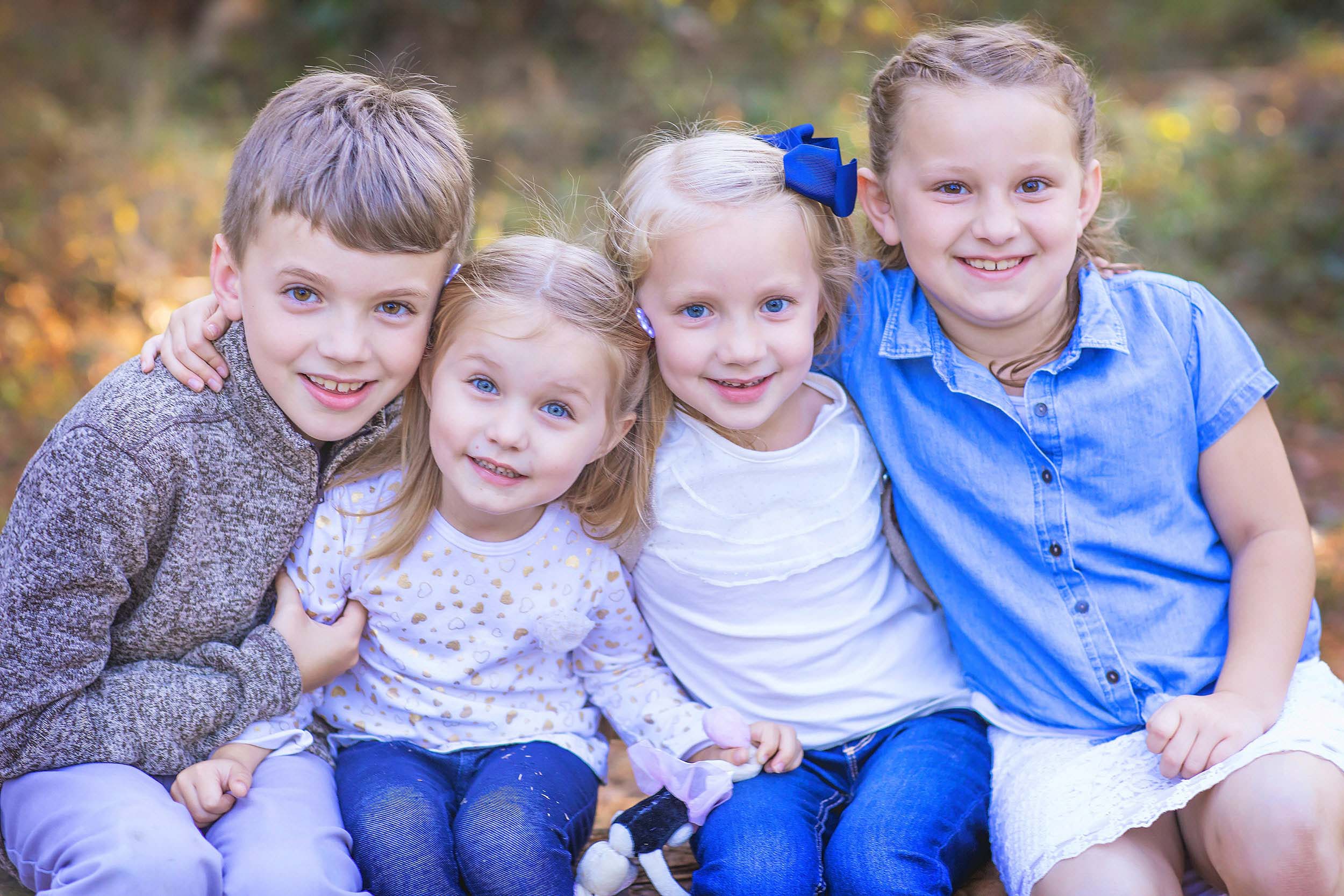  Outdoor portrait of four siblings hugging 