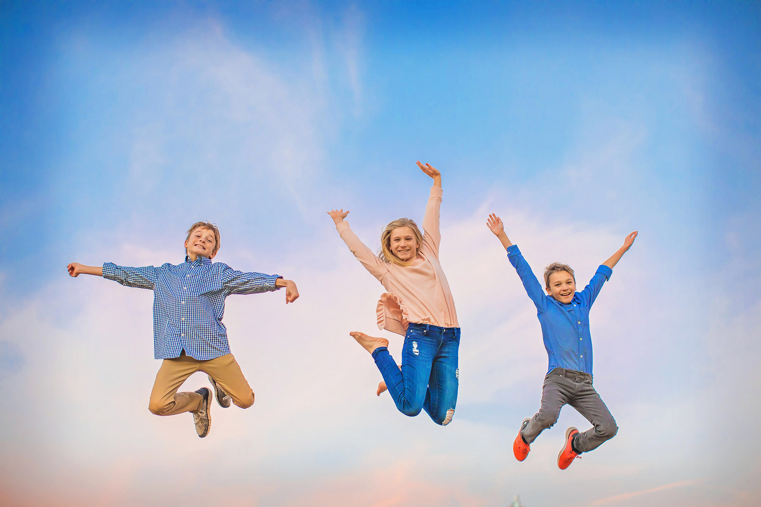  Tweens jumping in the dusky sky. Lifestyle portrait by spryART photography. 