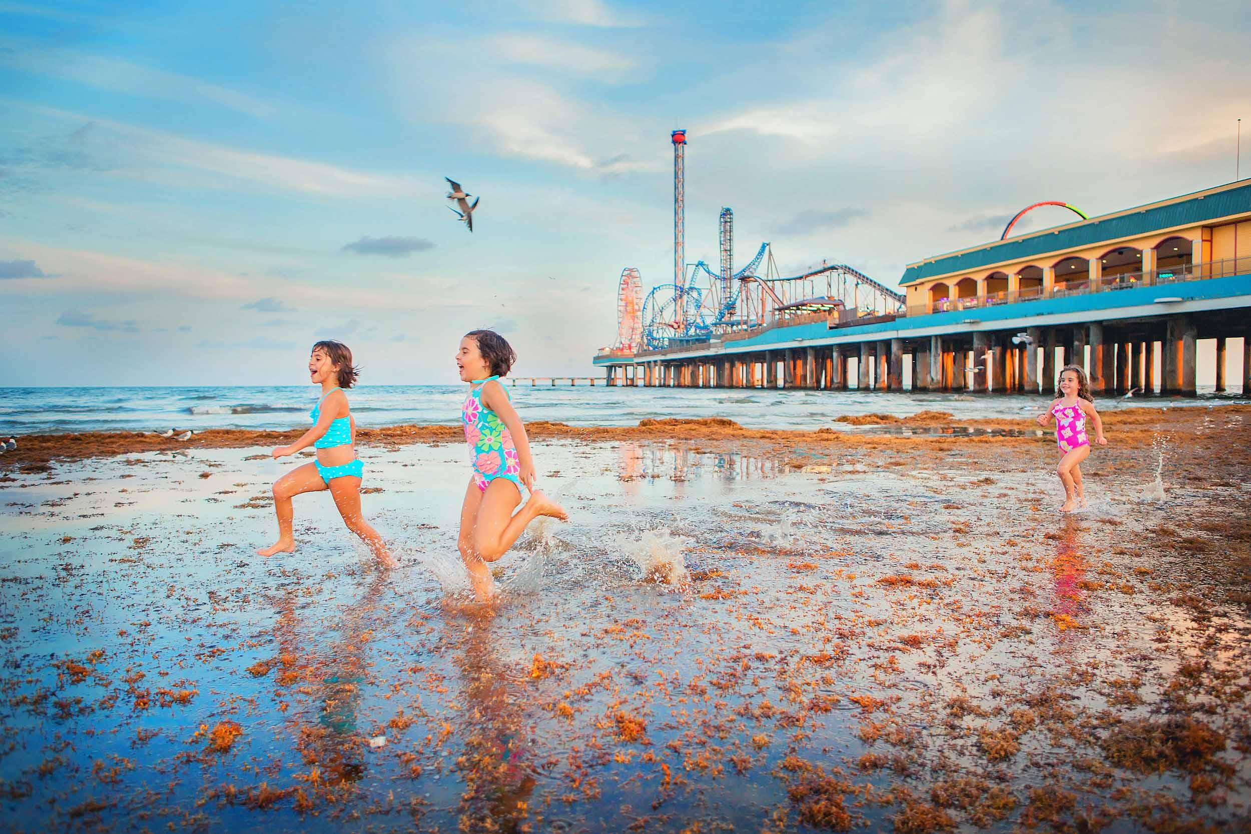  Young girls running on beach in Galveston Texas by Pleasure Pier by family photographer spryART photography 