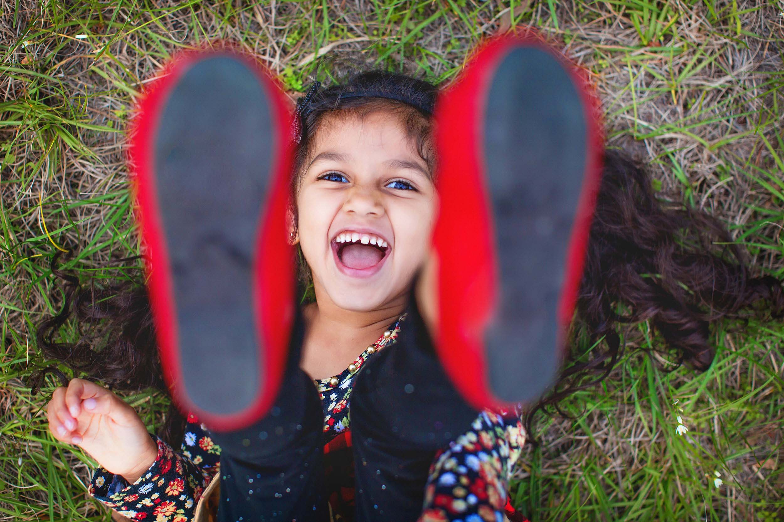  Lifestyle portrait of little girl in the grass laughing by spryART photography. 