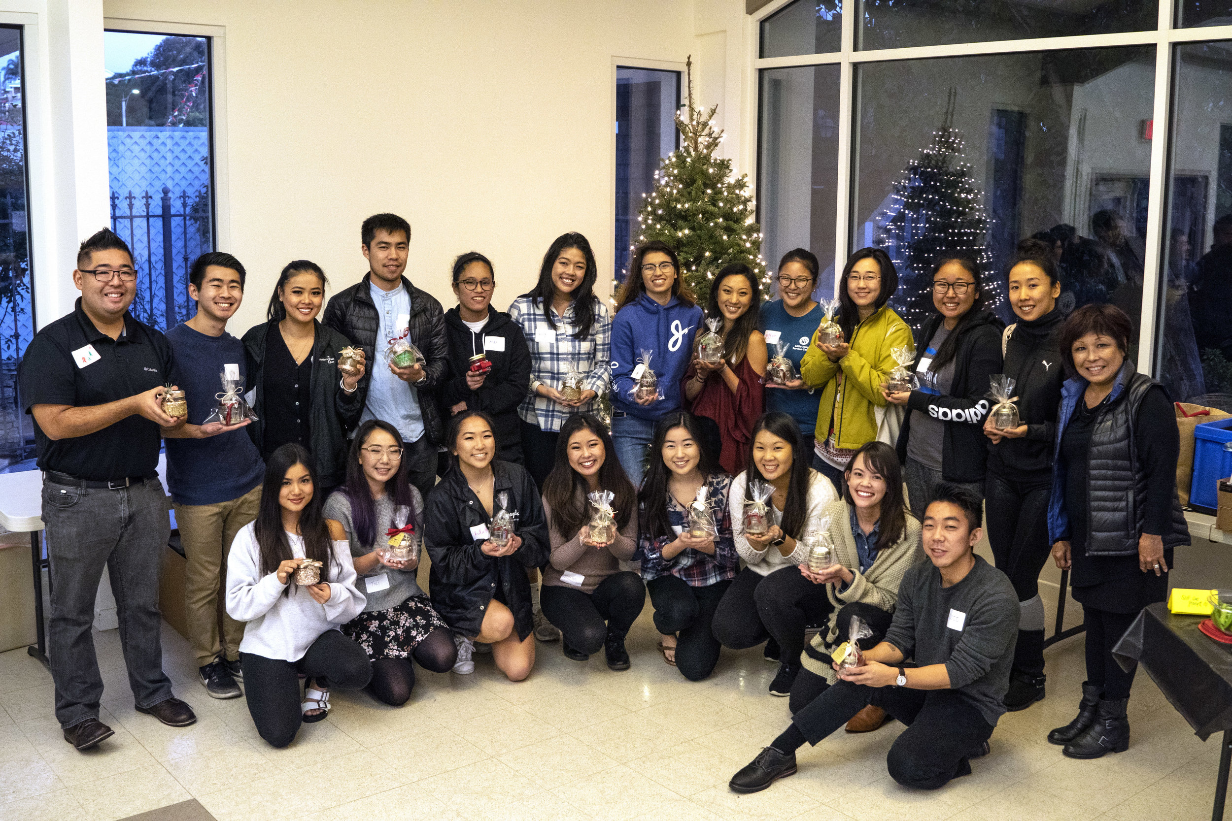 A large group smiles showing off the candles they have made.