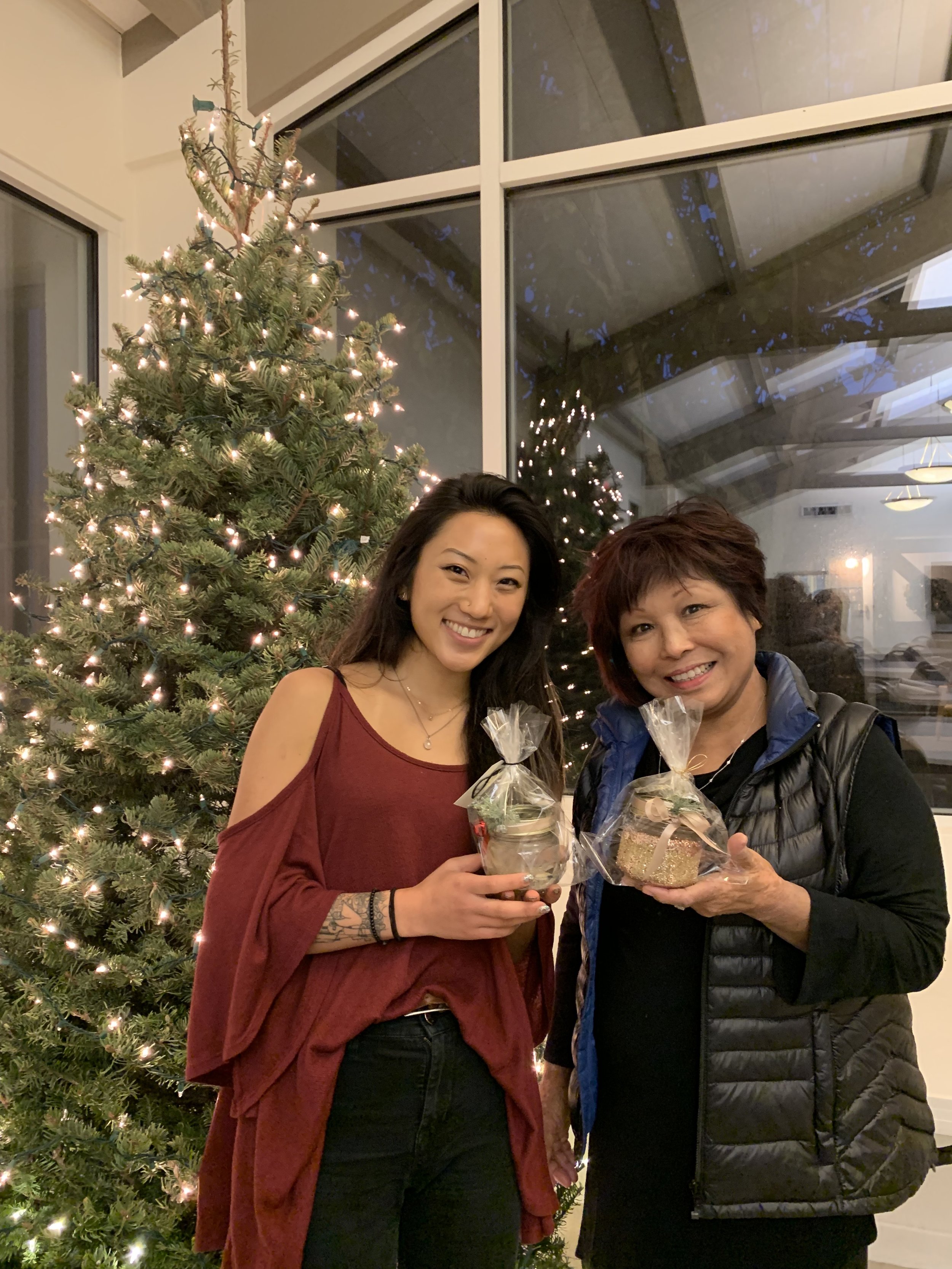 Two women smile while holding the candles they made.