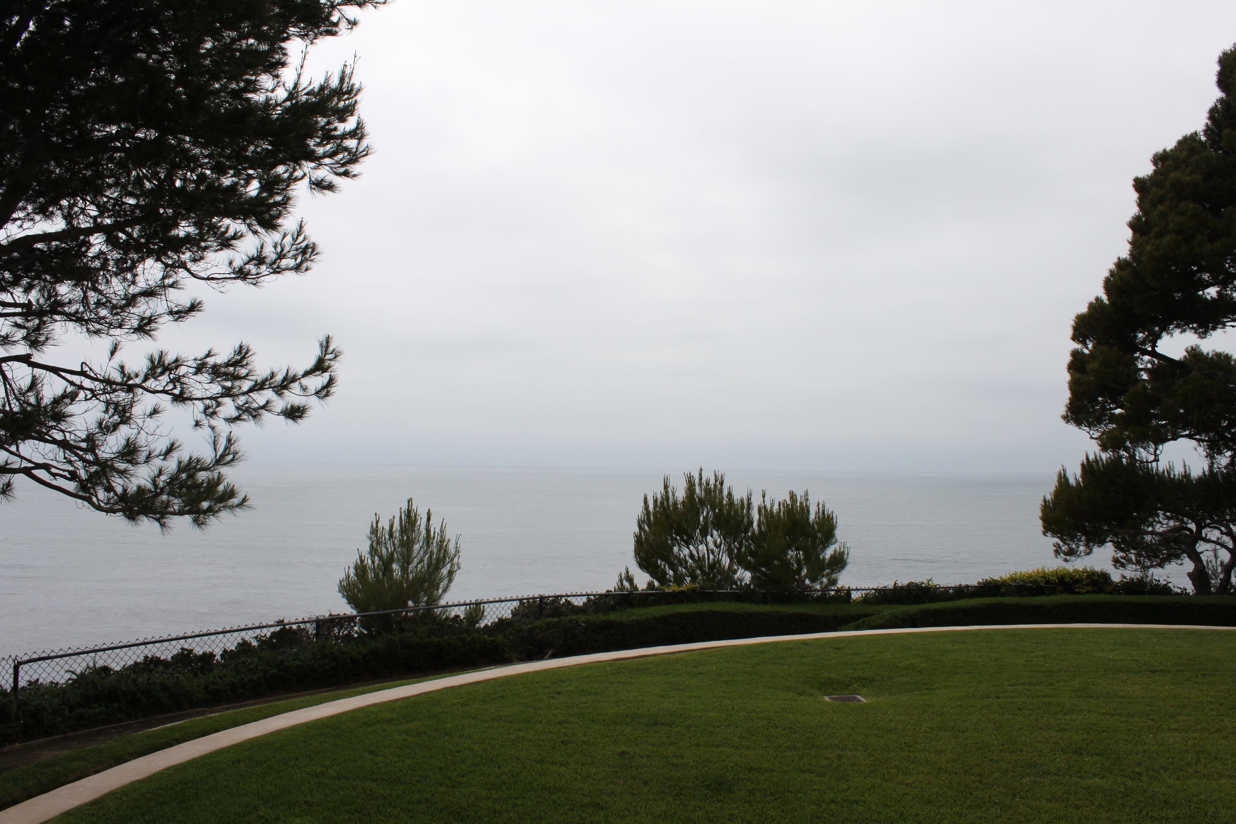 A view of the water beyond the manicured lawn is seen on an over-cased grey day.