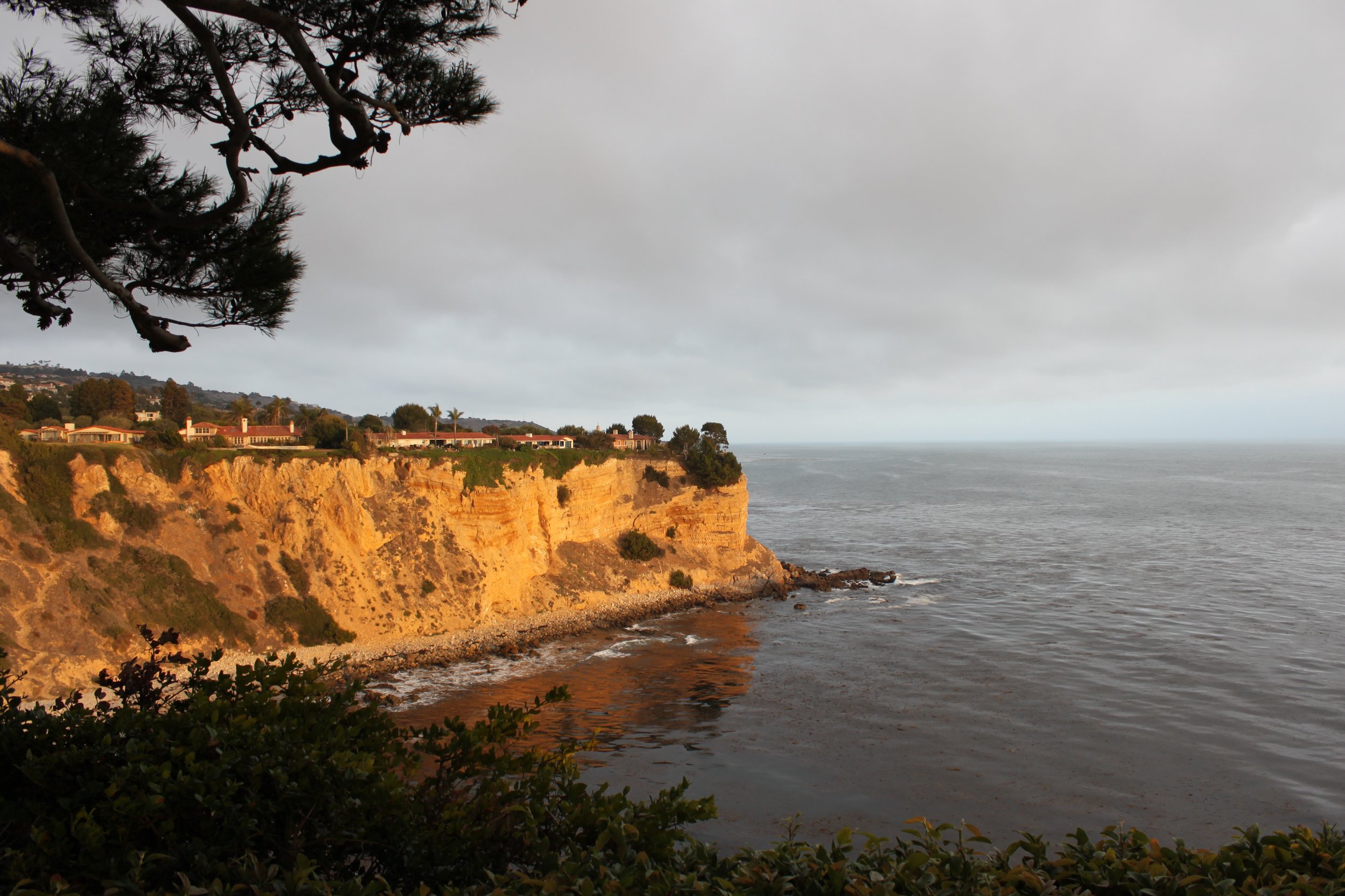 A cliff glows from the sun on the coast with water below. 