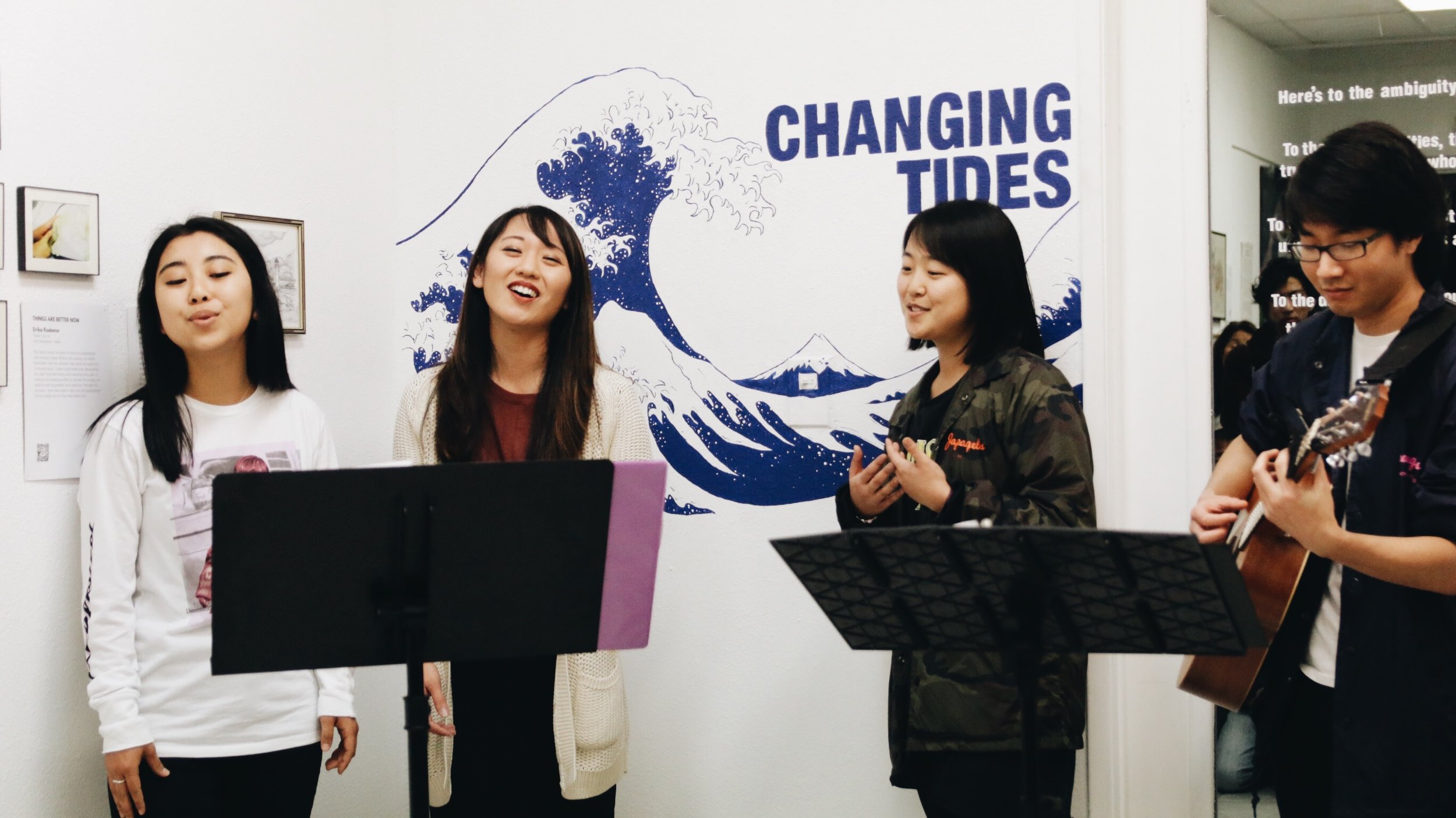 Three girls sing while a man plays the guitar.