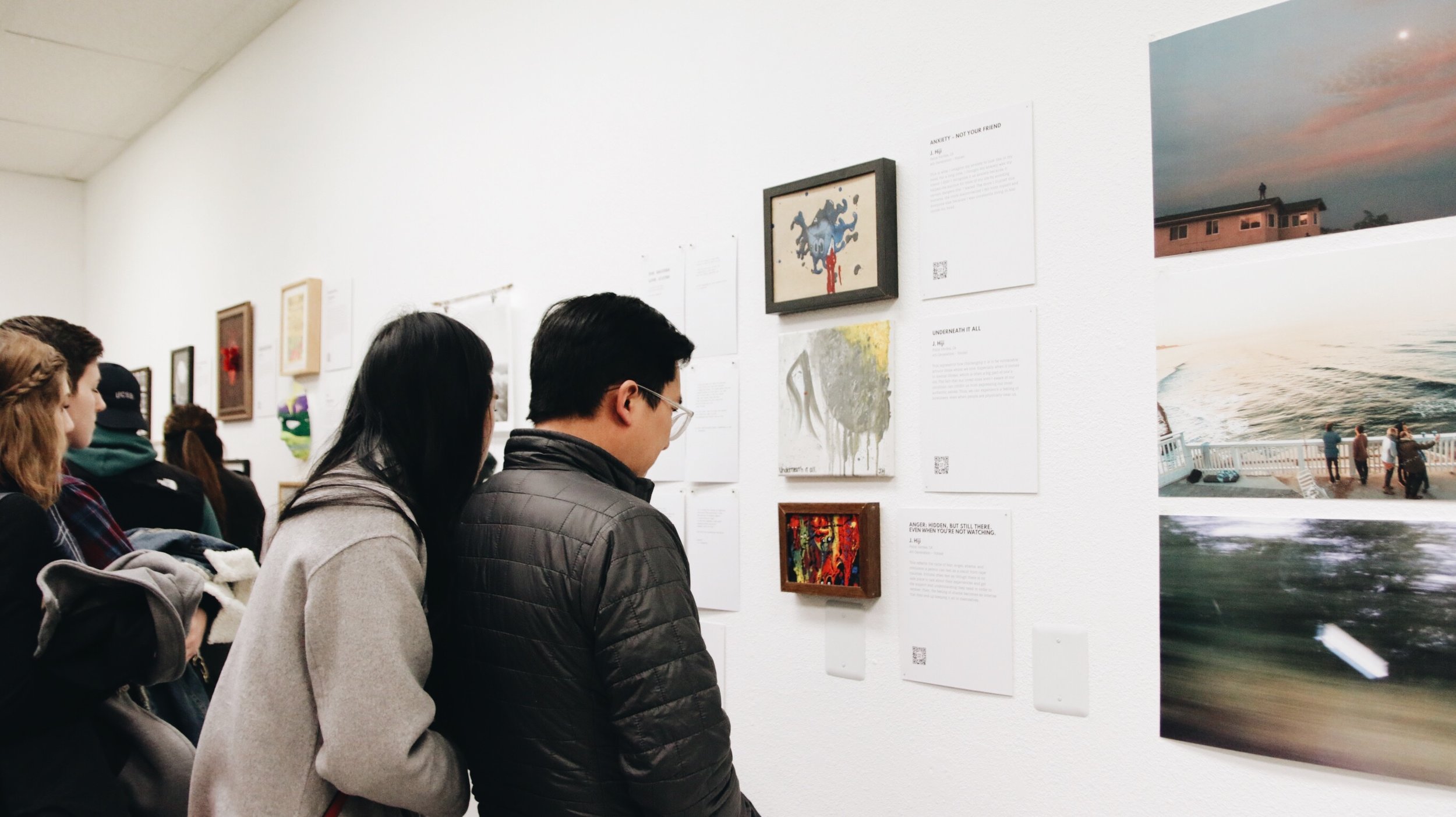 A man and a woman look at artwork on a wall. 