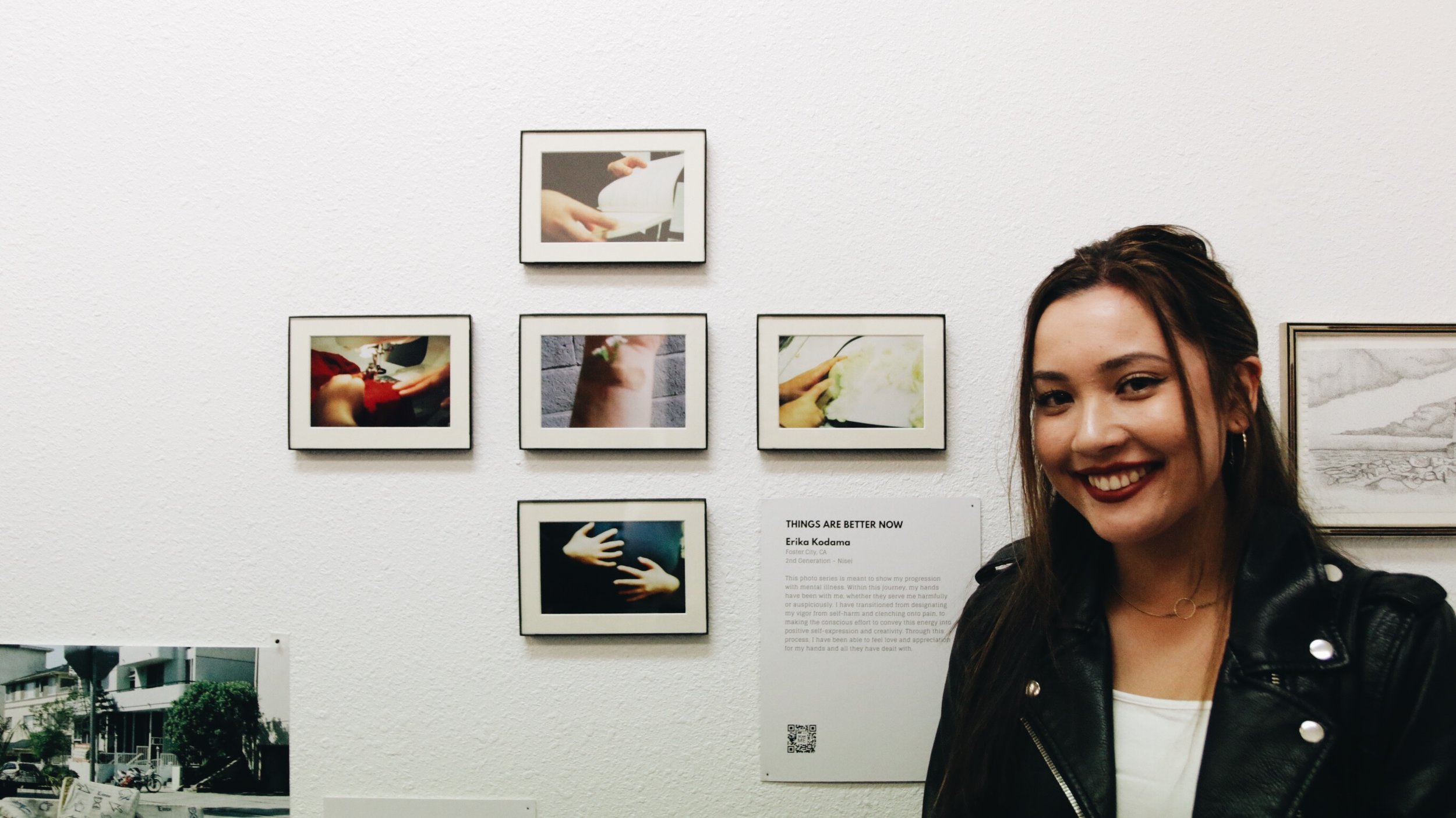 A woman smiles next to photographs called “These Are Better Now,” by Erika Kodoma.