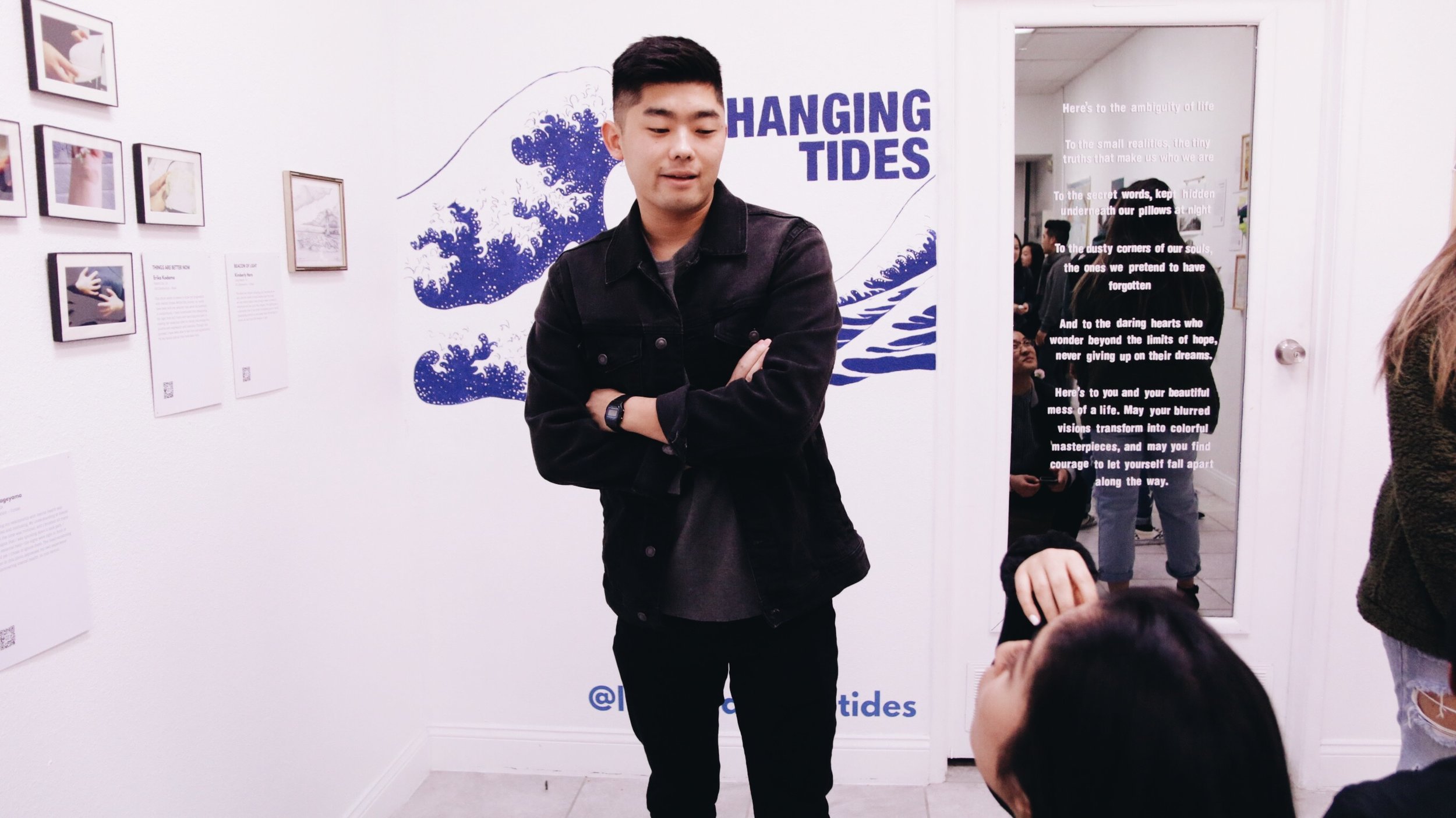 A man stands with his arms folded in front of the Changing Tides display in the gallery. 