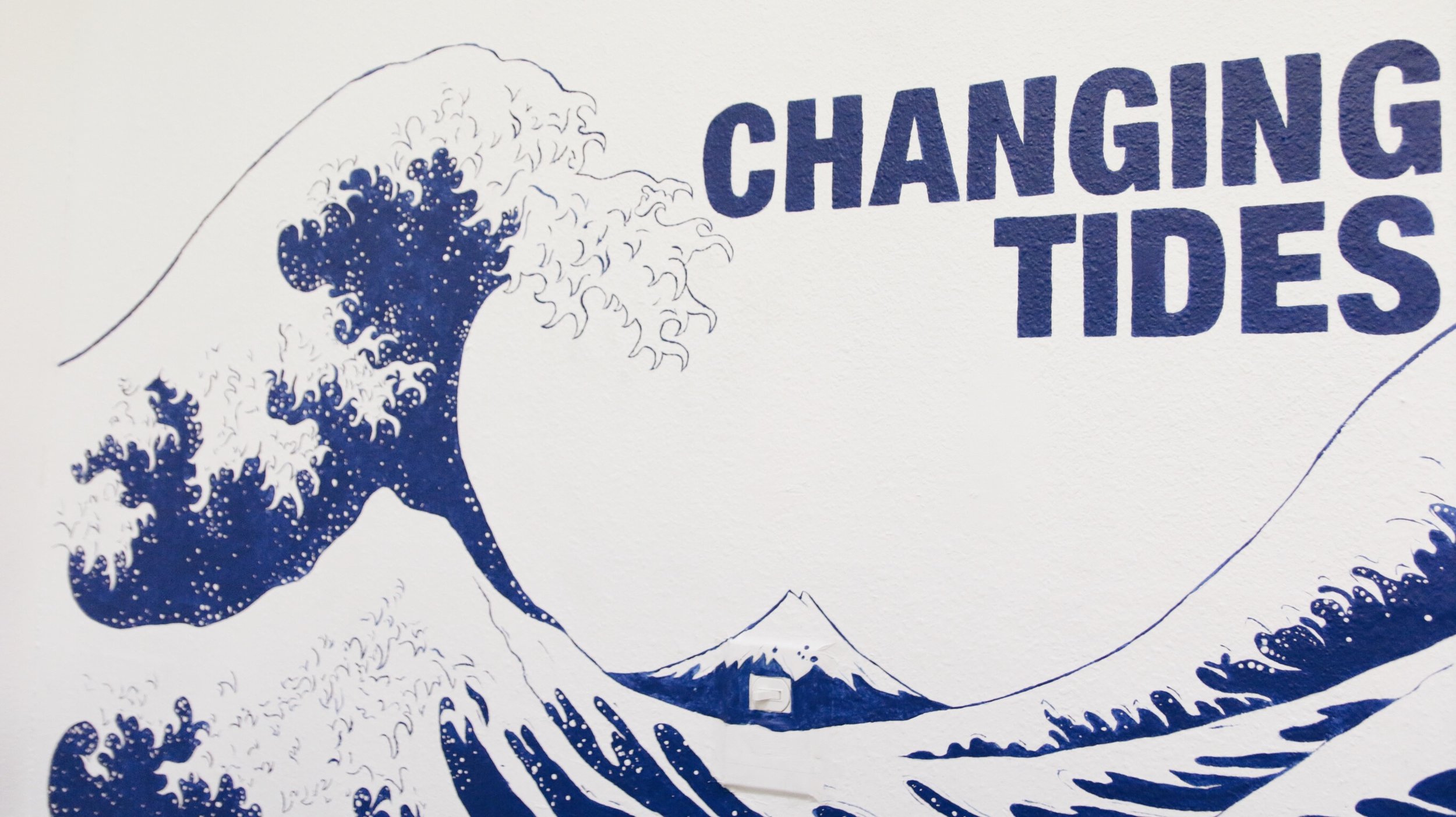 “Changing Tides” is painted on the wall with the logo of a wave.