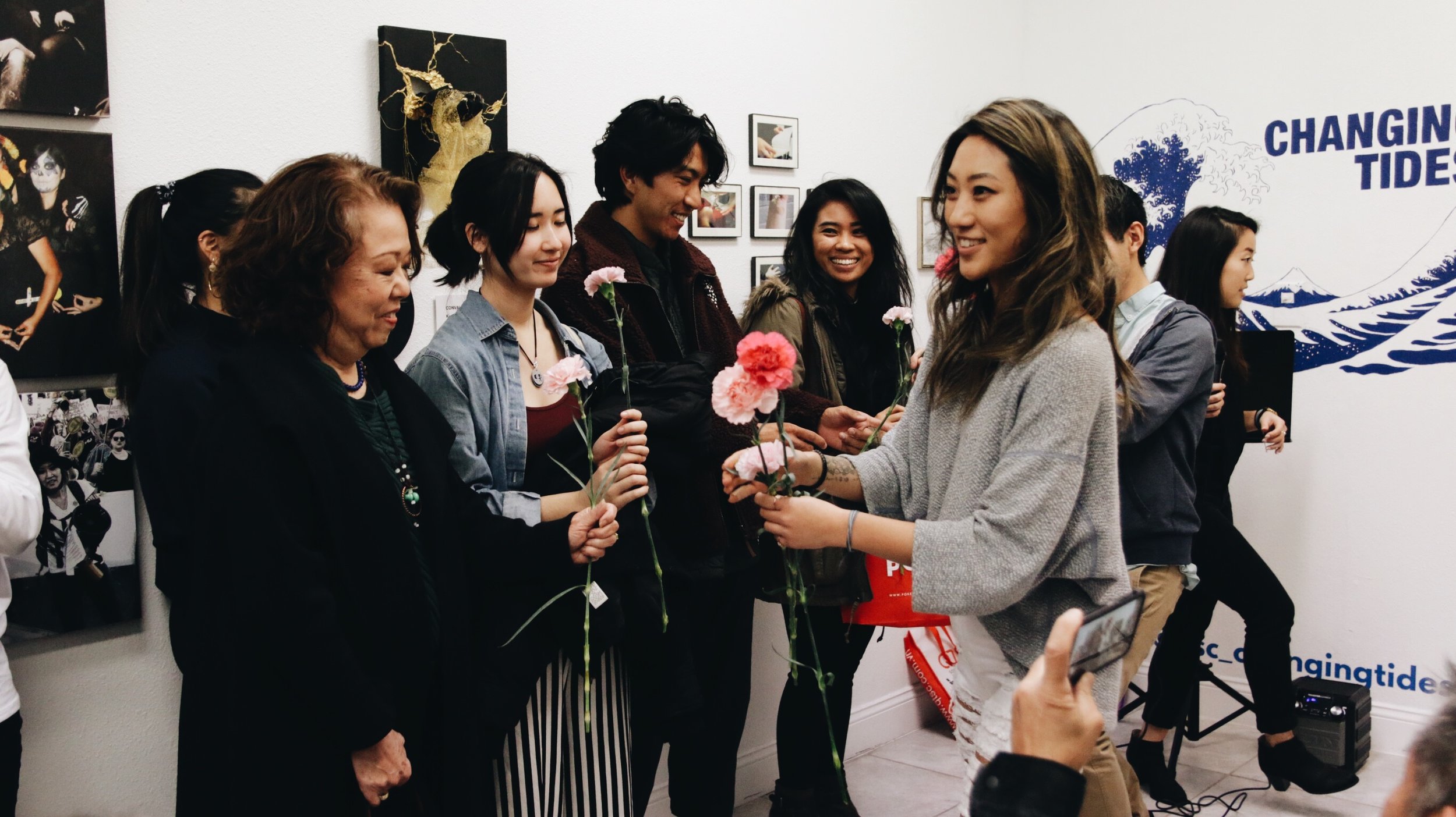 A woman gives others pink carnations in the gallery.