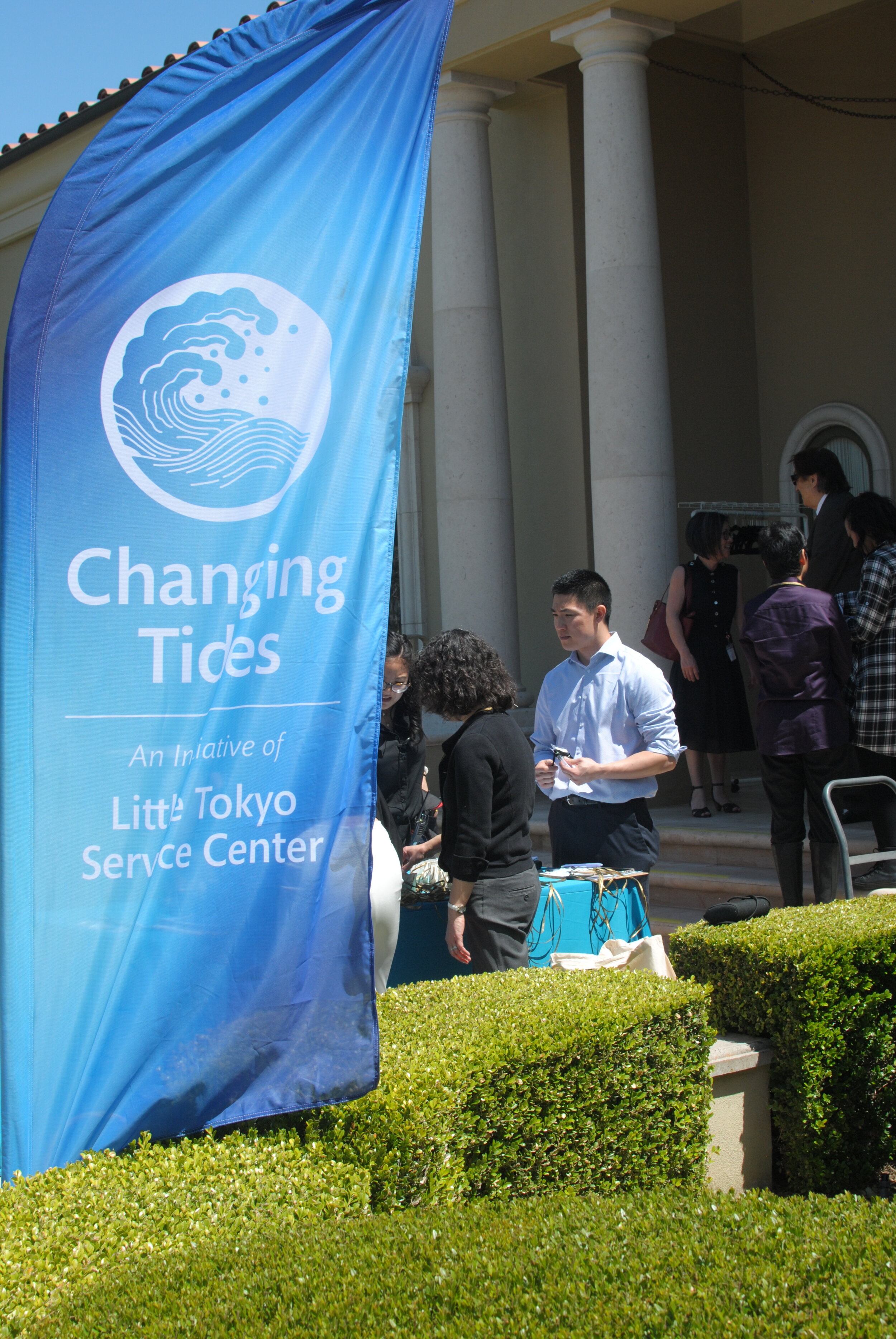 People stand at a table behind a banner that reads “Changing Tides: An Initiative of Little Tokyo Service Center.”