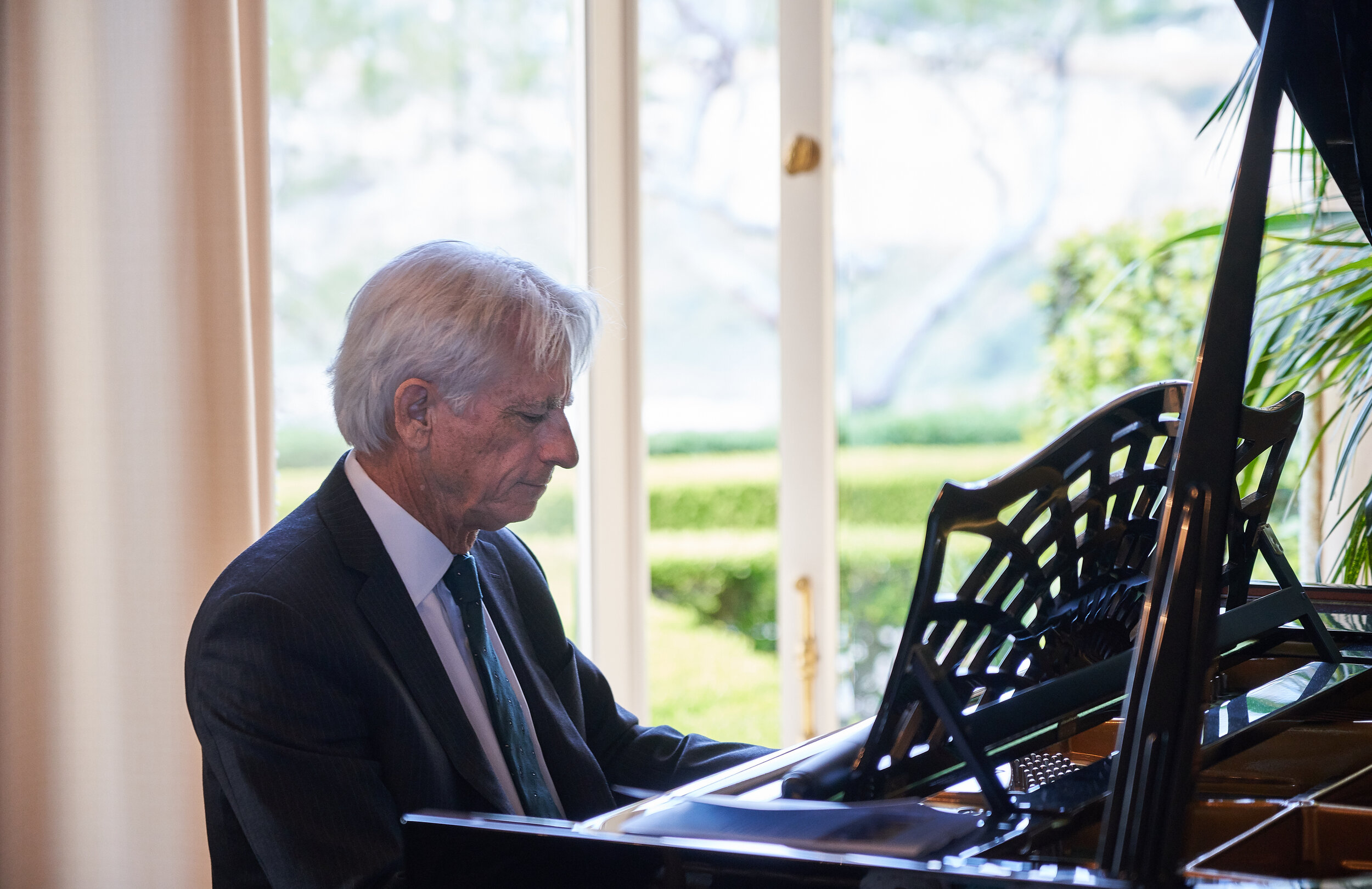 A man with white hair plays the piano. 