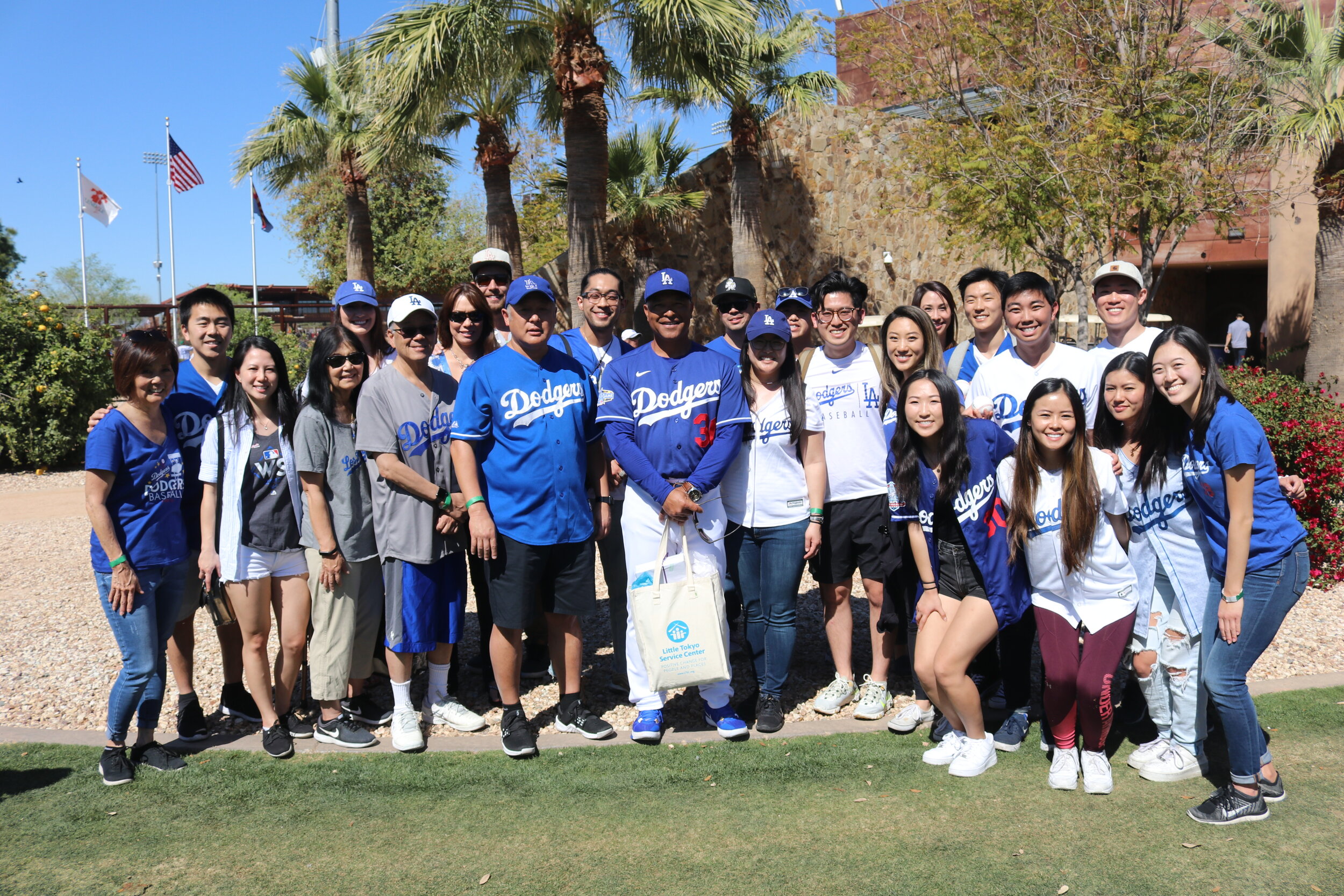 A large group of fans smile with a man in a Dodgers uniform. 