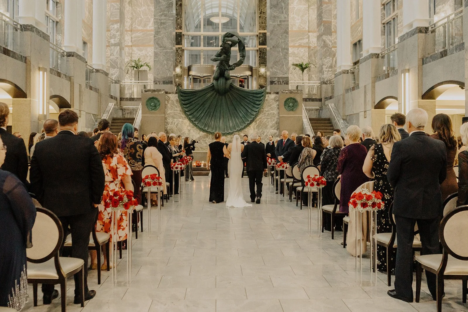 A bride walks down the aisle in the atrium at her Pazzos 311 Chicago wedding.