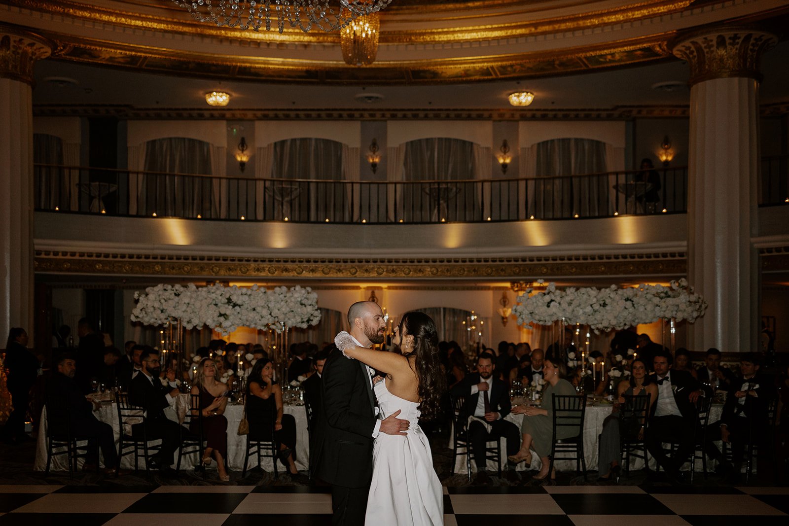 A bride and groom share a first dance on a black & white checkered dance floor at their Intercontinental Chicago wedding reception.