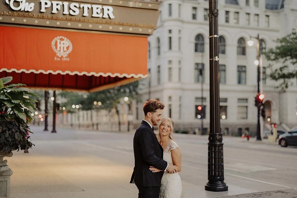 Newlyweds are photographed on the sidewalk outside their Pfister Hotel wedding