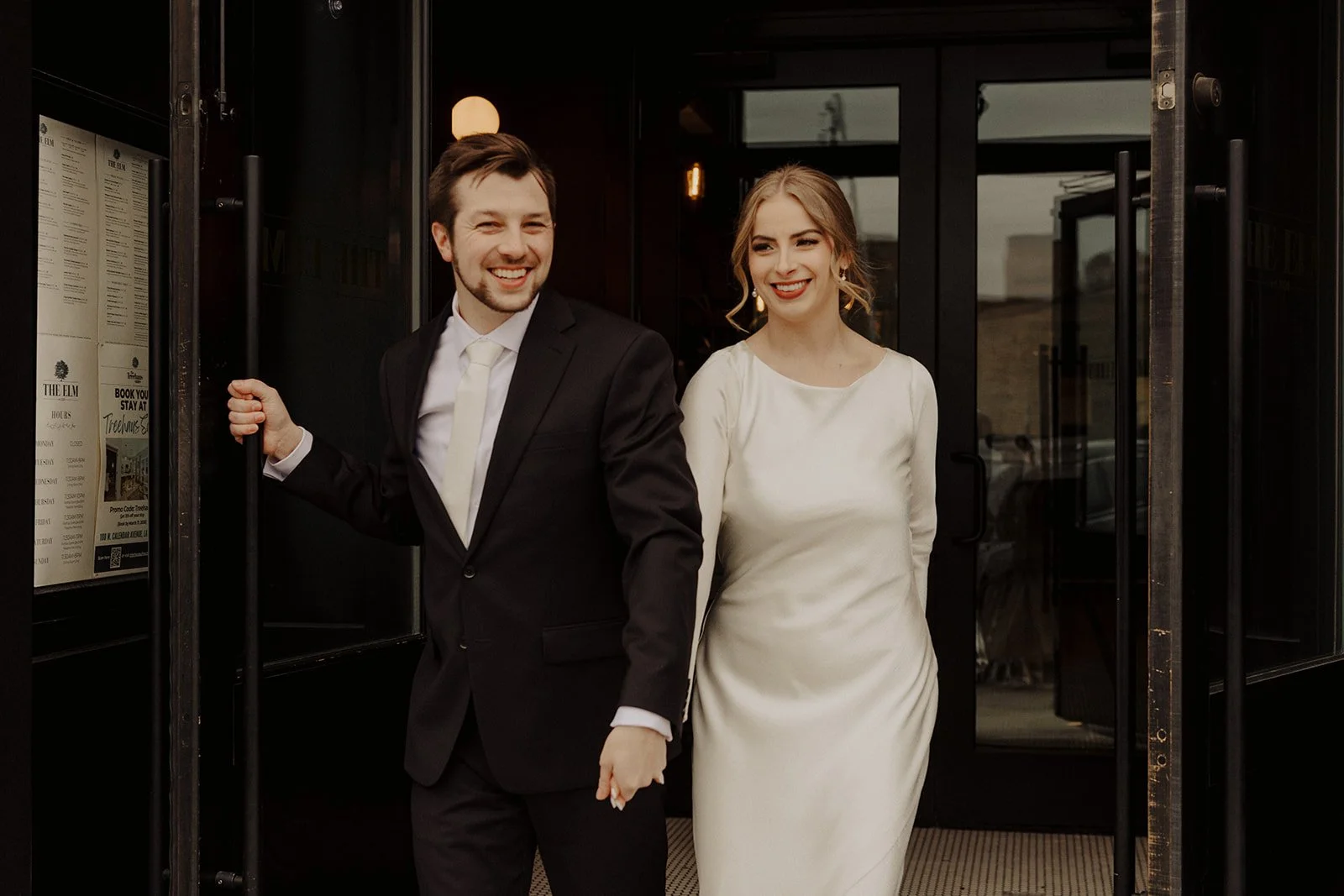 Newlyweds hold hands as they exit through the front doors of  The Elm Lagrange IL where they held their intimate civil ceremony