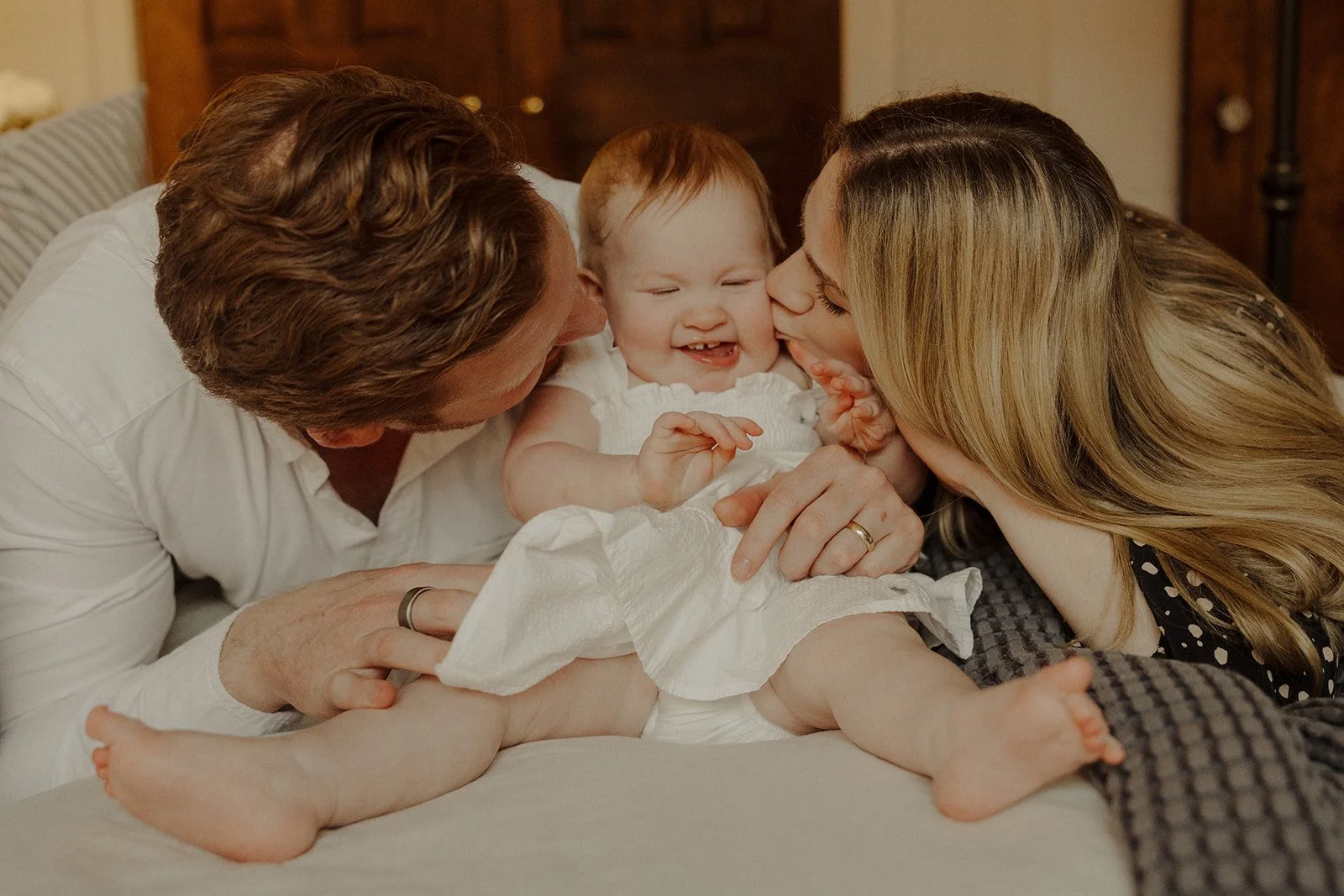 Parents kiss the cheeks of their baby girl during in home family photos Chicago.