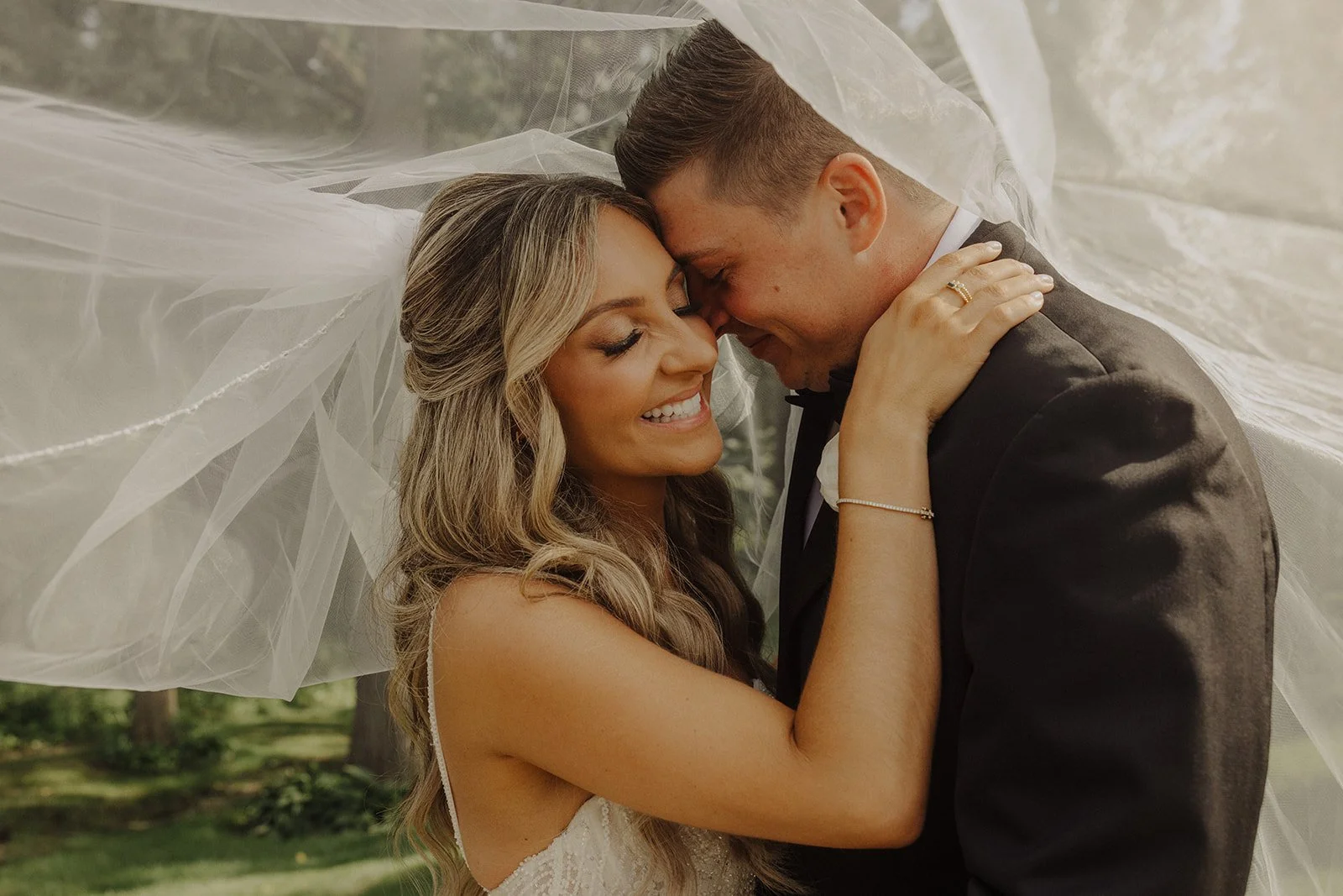 A bride and groom embrace beneath a veil during bridal portraits at their monte bello estate wedding