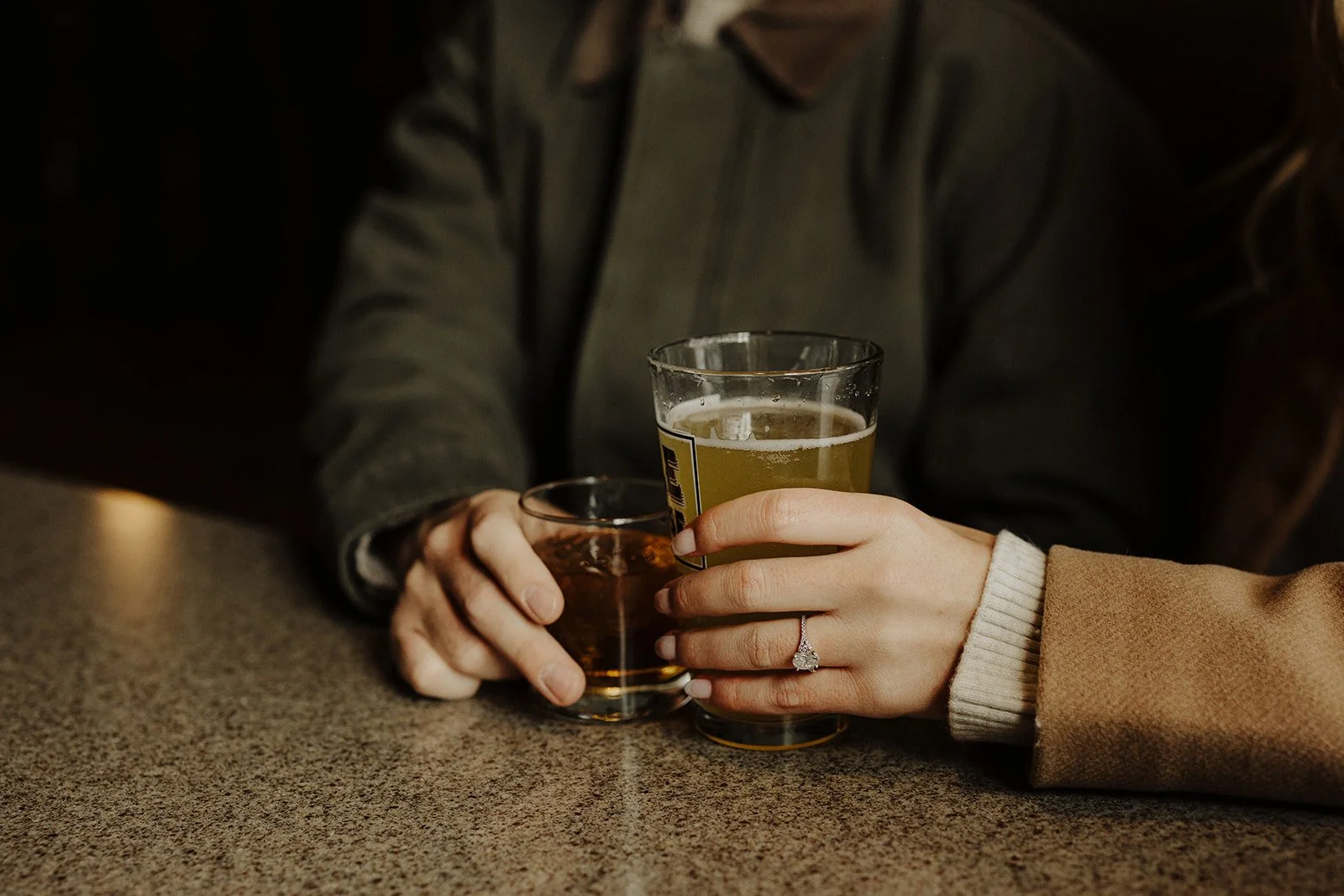 A close up showcases an oval cut diamond engagement ring during engagement photos at Geneva Ale House in geneva Il